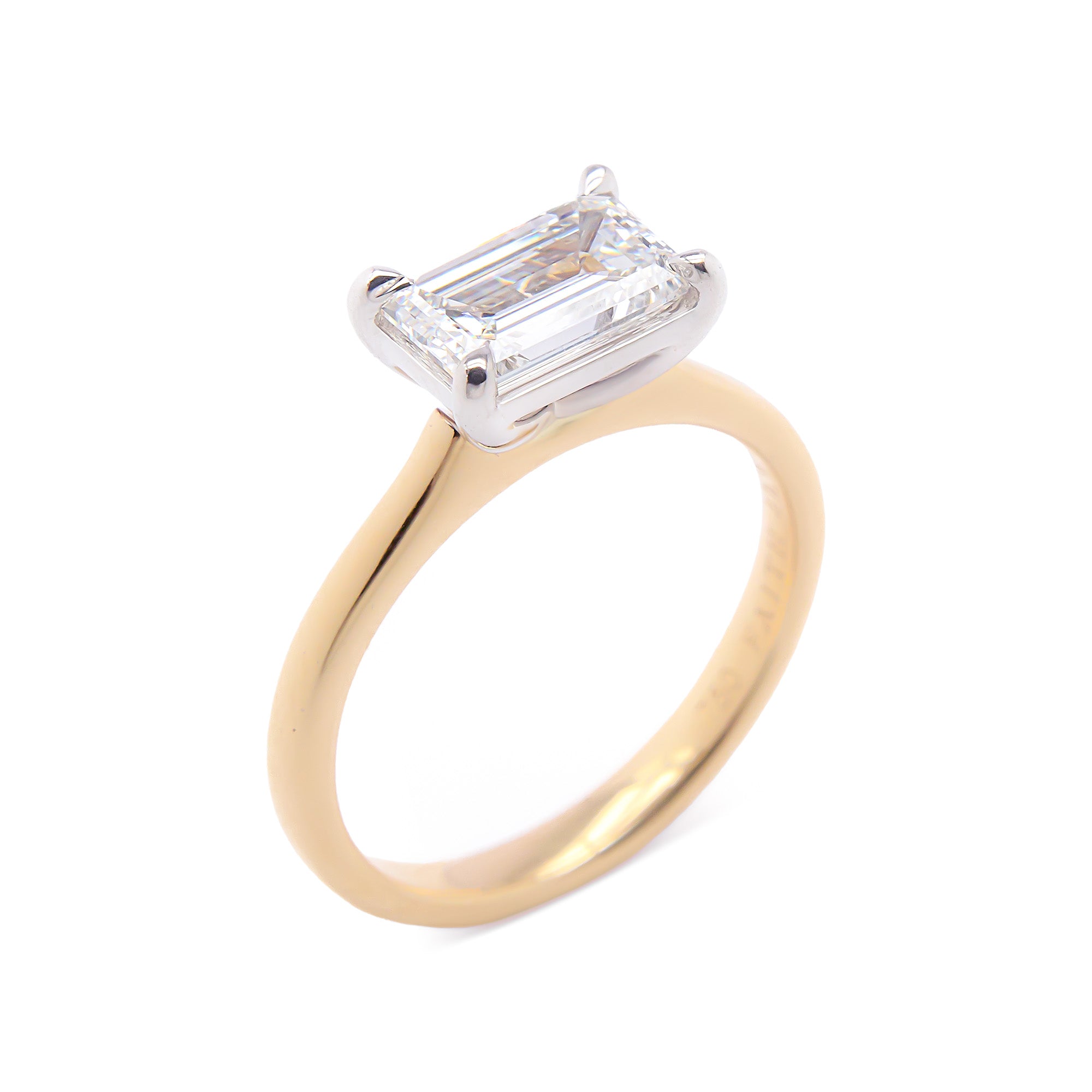 Emerald-cut East-West Engagement Diamond Ring in yellow gold with white gold claws, a modern yet timeless elegant design.
