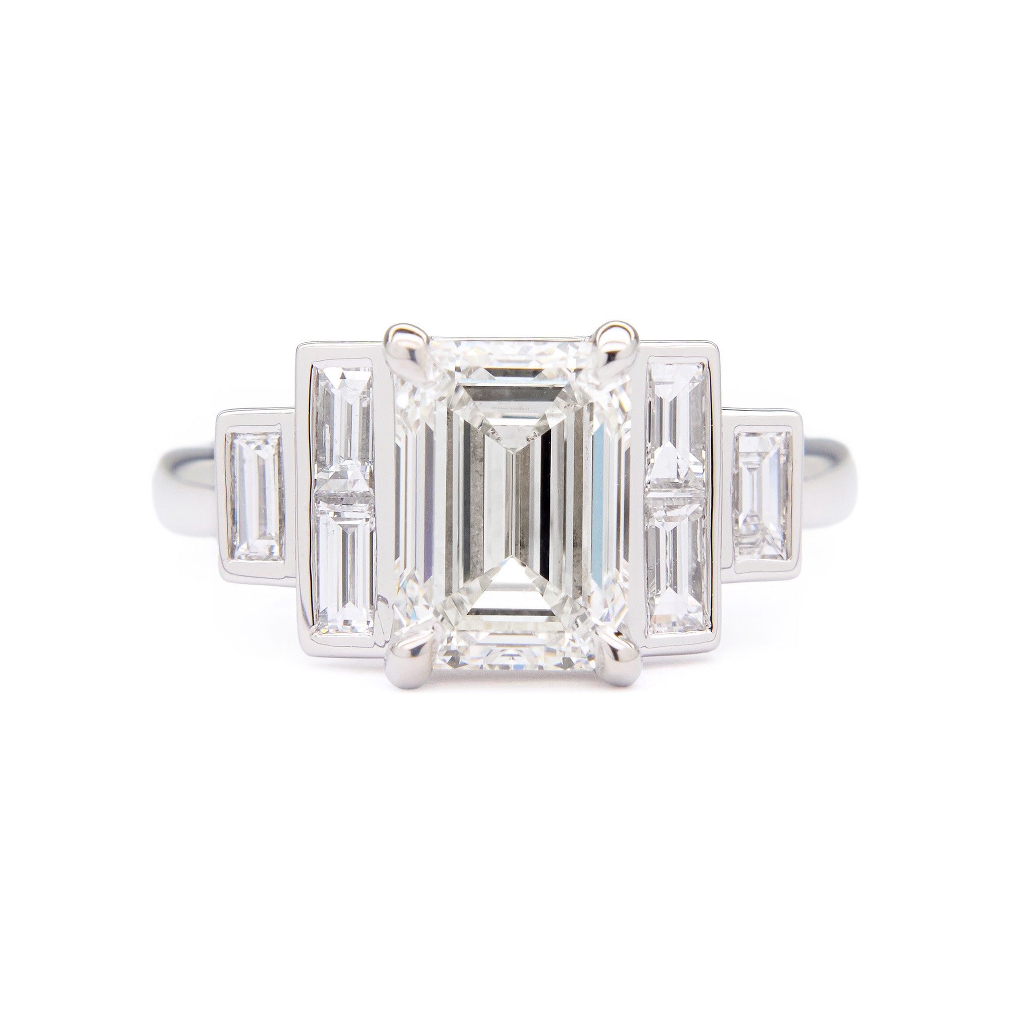Diamond engagement ring with emerald-cut center stone and baguette side stones on a white background