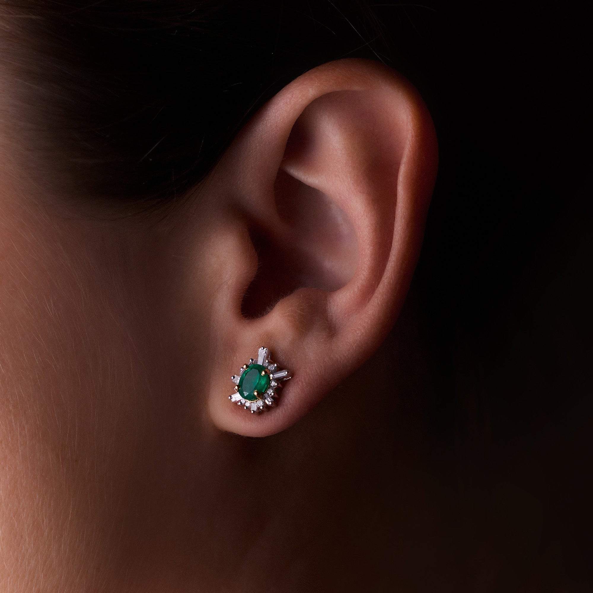 Oval-cut emerald sunburst earrings with white diamonds in yellow gold, radiant and elegant design, worn on model.