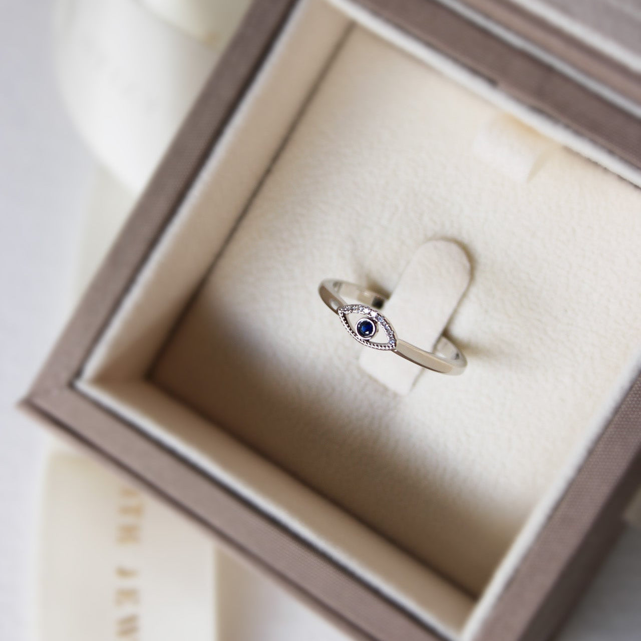 Minimal evil eye ring featuring a blue sapphire and white diamonds set in platinum.