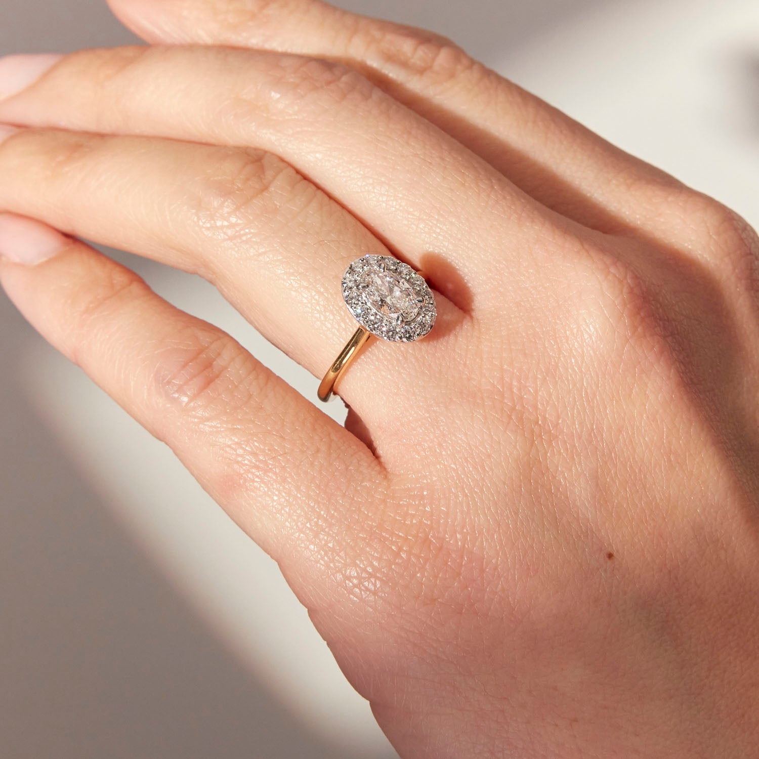 Faith Jewels Amelia Diamond Halo engagement ring featuring an oval-shaped center diamond encircled by a halo of round brilliant diamonds, set on a sleek yellow gold band