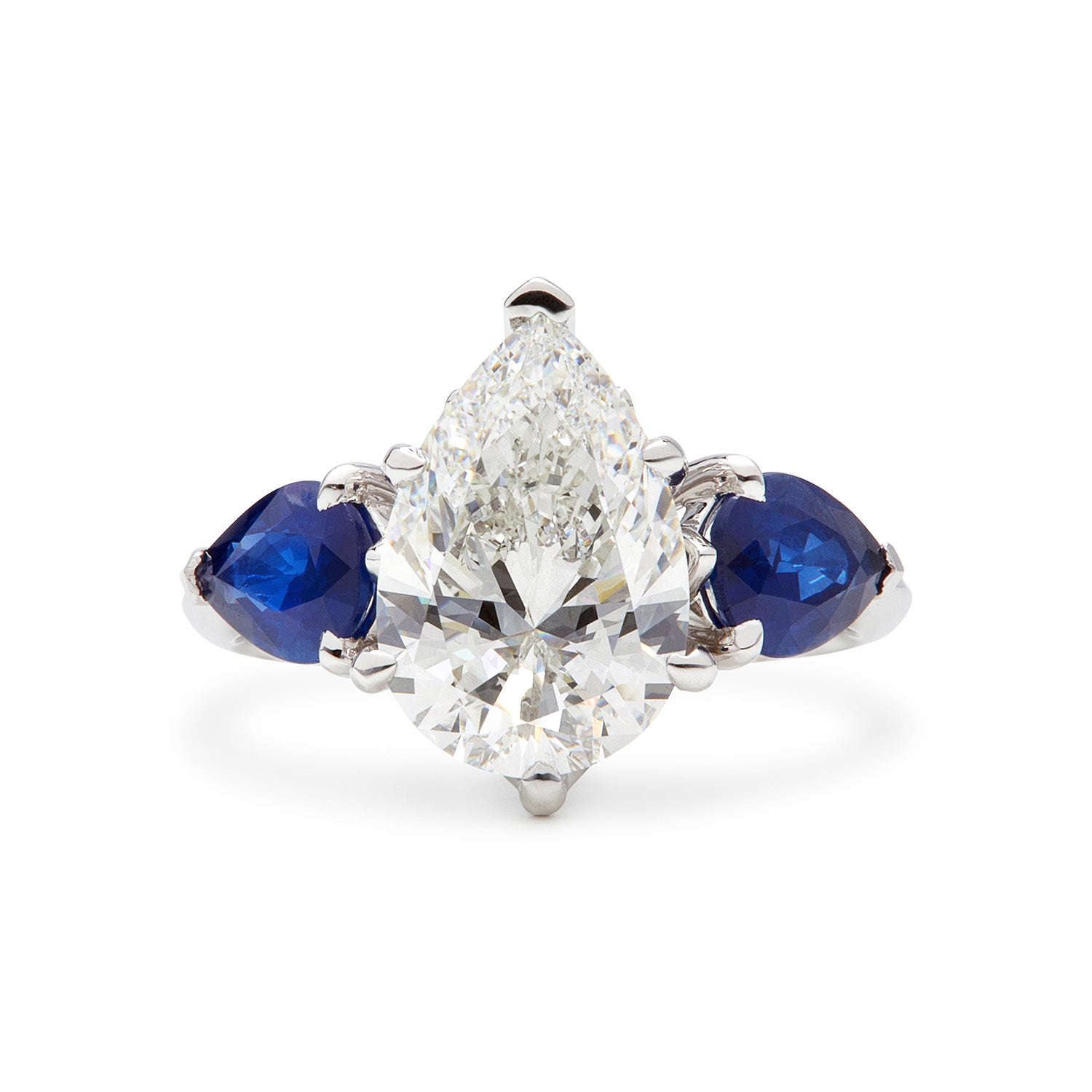 Faith Jewels Belle Époque engagement ring featuring a pear-cut diamond center, flanked by pear-cut blue sapphires, set in 18k white gold with elegant sweeping claws
