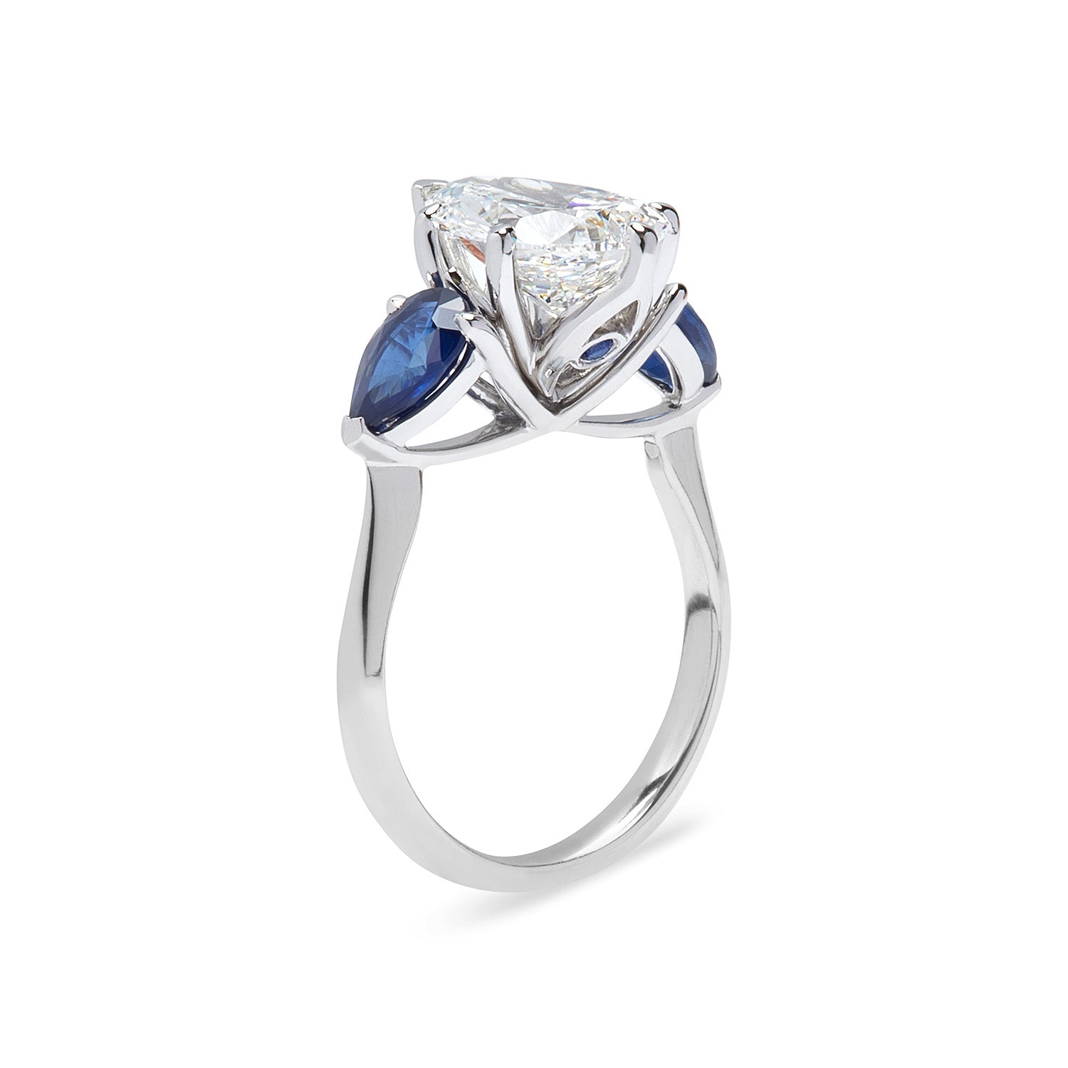 Faith Jewels Belle Époque engagement ring featuring a pear-cut diamond center, flanked by pear-cut blue sapphires, set in 18k white gold with elegant sweeping claws, accent sapphire stone seated underneath the diamond