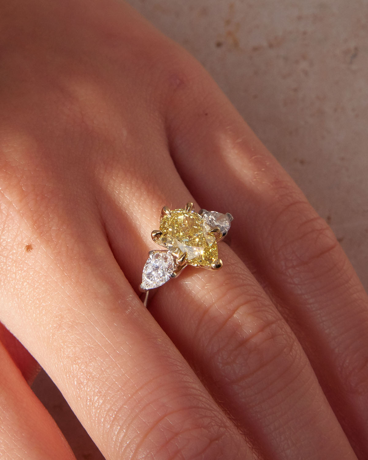 Belle Époque engagement ring with a pear-cut yellow diamond center, flanked by pear-cut white diamonds, set in 18k white gold