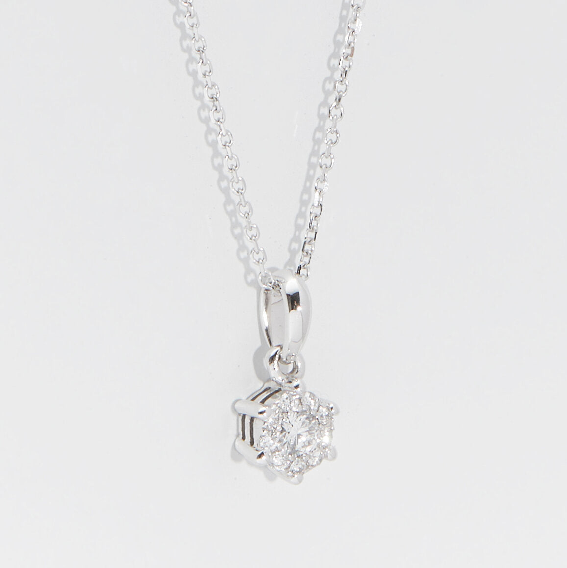 Diamond Cluster Pendant Necklace in 18k white gold featuring a central round diamond with a pavé-set halo on a fine adjustable white gold trace chain