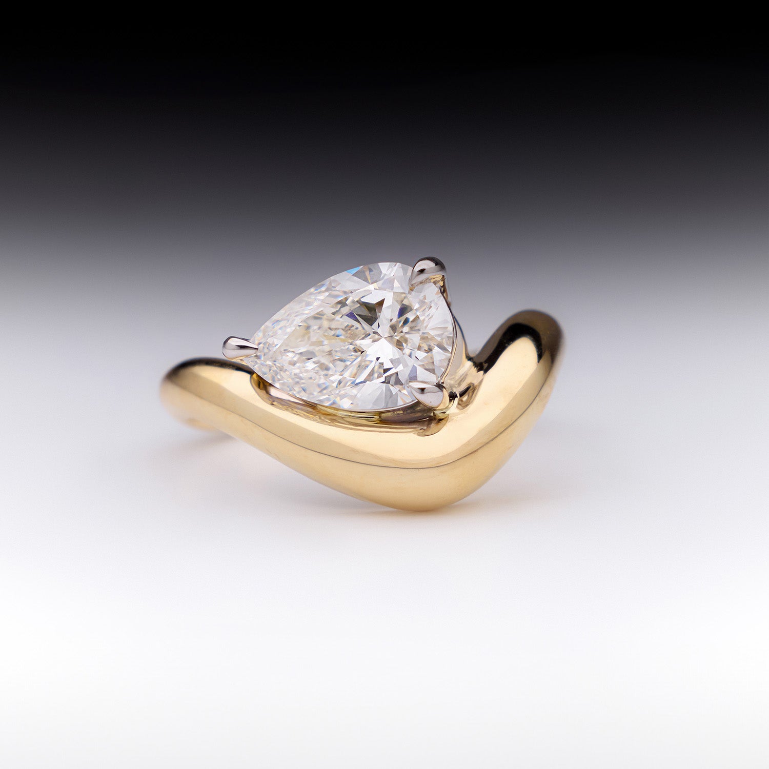 FJ Engagement Ring featuring a pear cut diamond set in a bold, curved yellow gold band with a sculptural, contemporary design