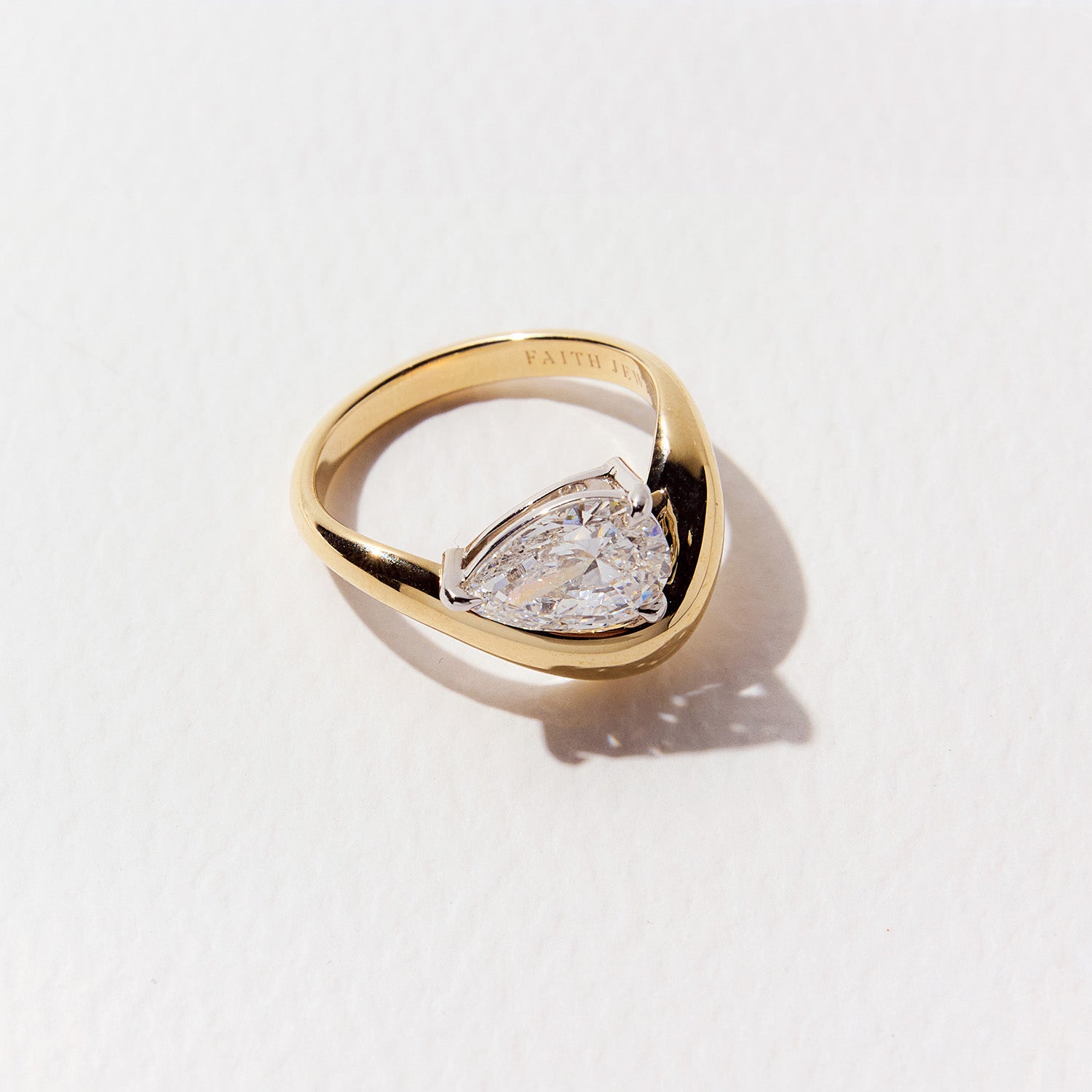 FJ Engagement Ring featuring a pear cut diamond set in a bold, curved yellow gold band with a sculptural, contemporary design