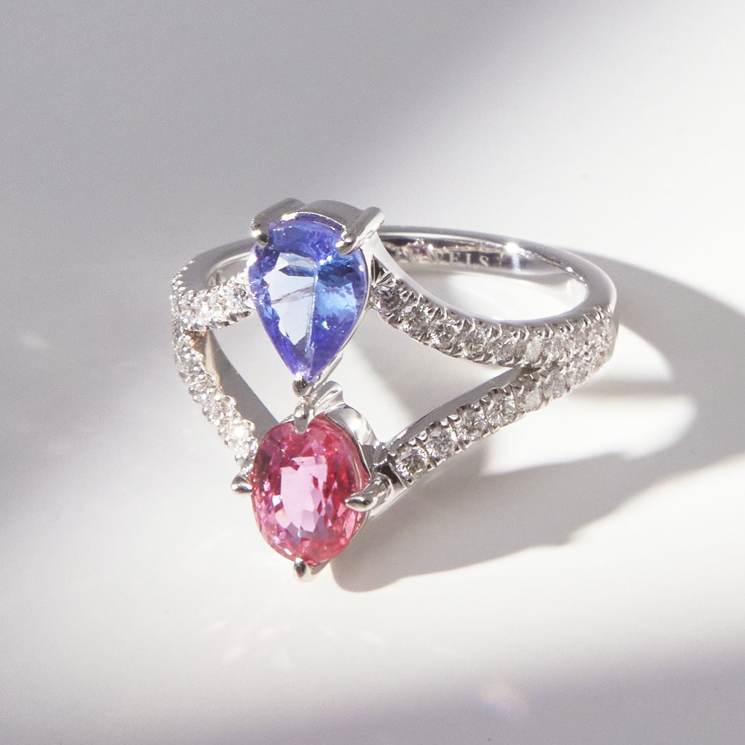 Faith Jewels Elsie ring in 18k white gold featuring a pear-cut tanzanite and a pink sapphire, set on a split diamond white gold band