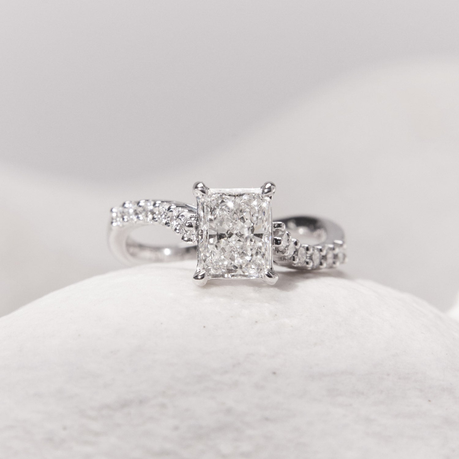 Faith Jewels Infinite Love Diamond ring featuring intertwined infinity loops, a radiant emerald-cut diamond center, and diamond-accented 18k white gold band