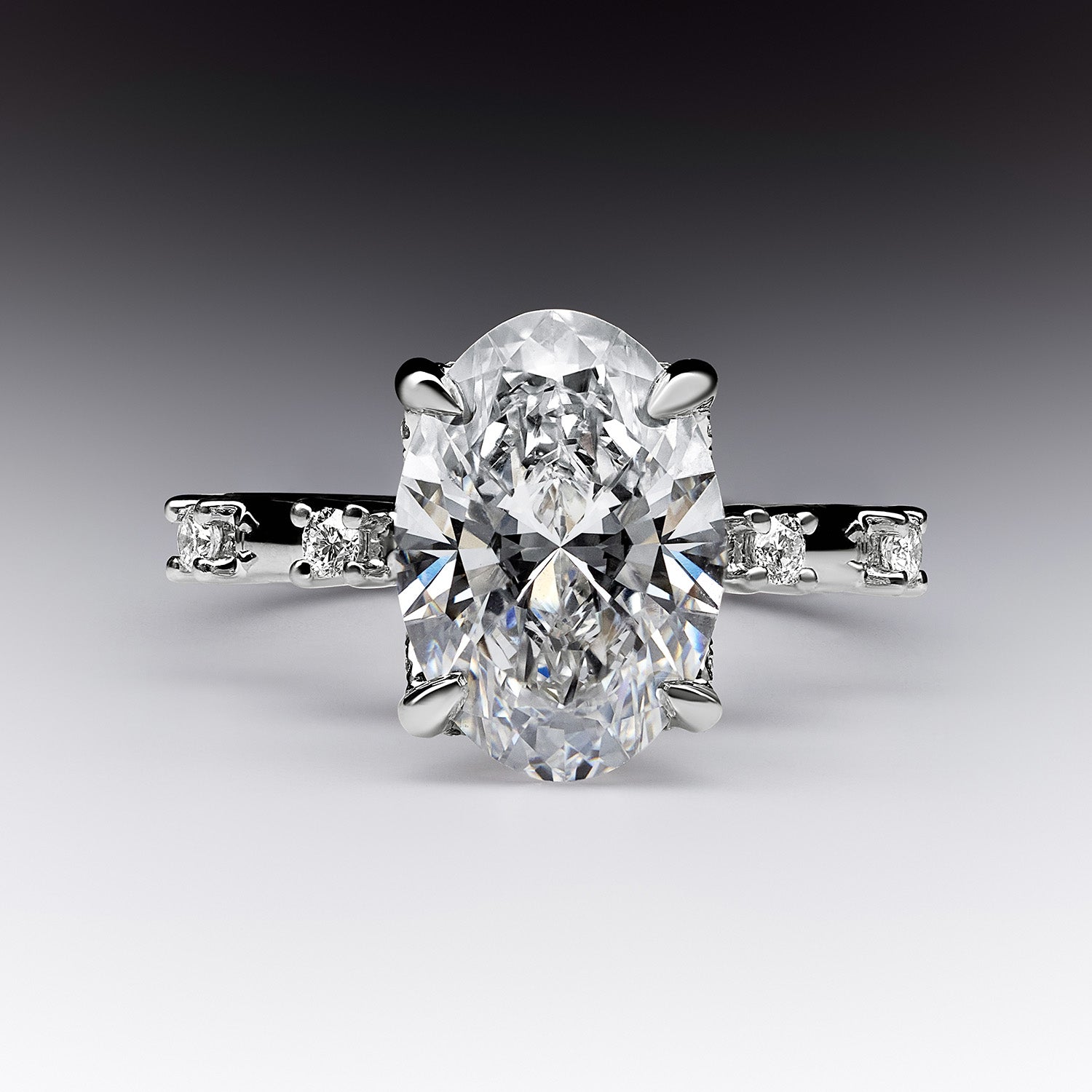 Faith Jewels Katherine diamond engagement ring with a central oval-cut white diamond, accented by four diamonds on an 18k white gold band.