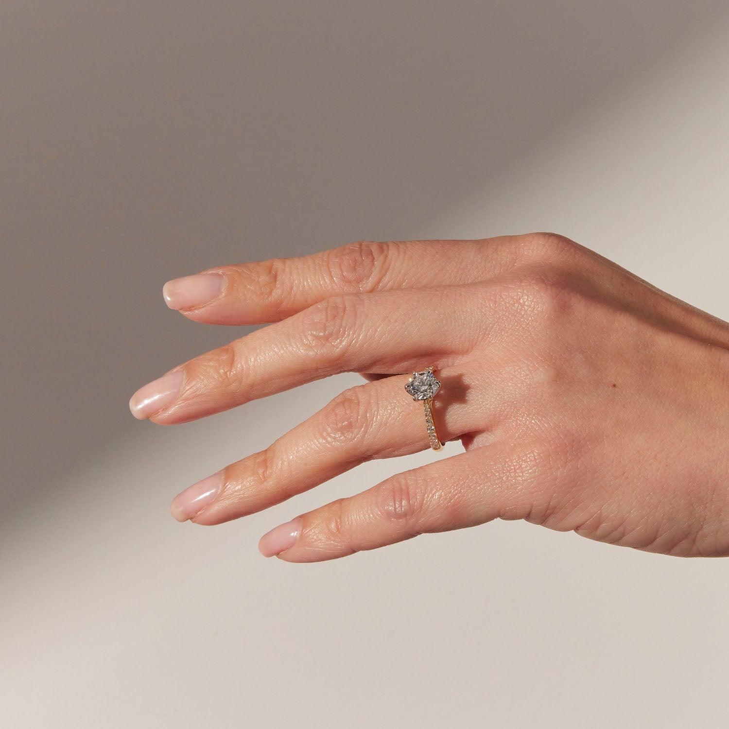 Faith Jewels Miriam diamond engagement ring featuring a round cut diamond solitaire with a blue sapphire beneath, set in a diamond-accented 18k yellow gold band