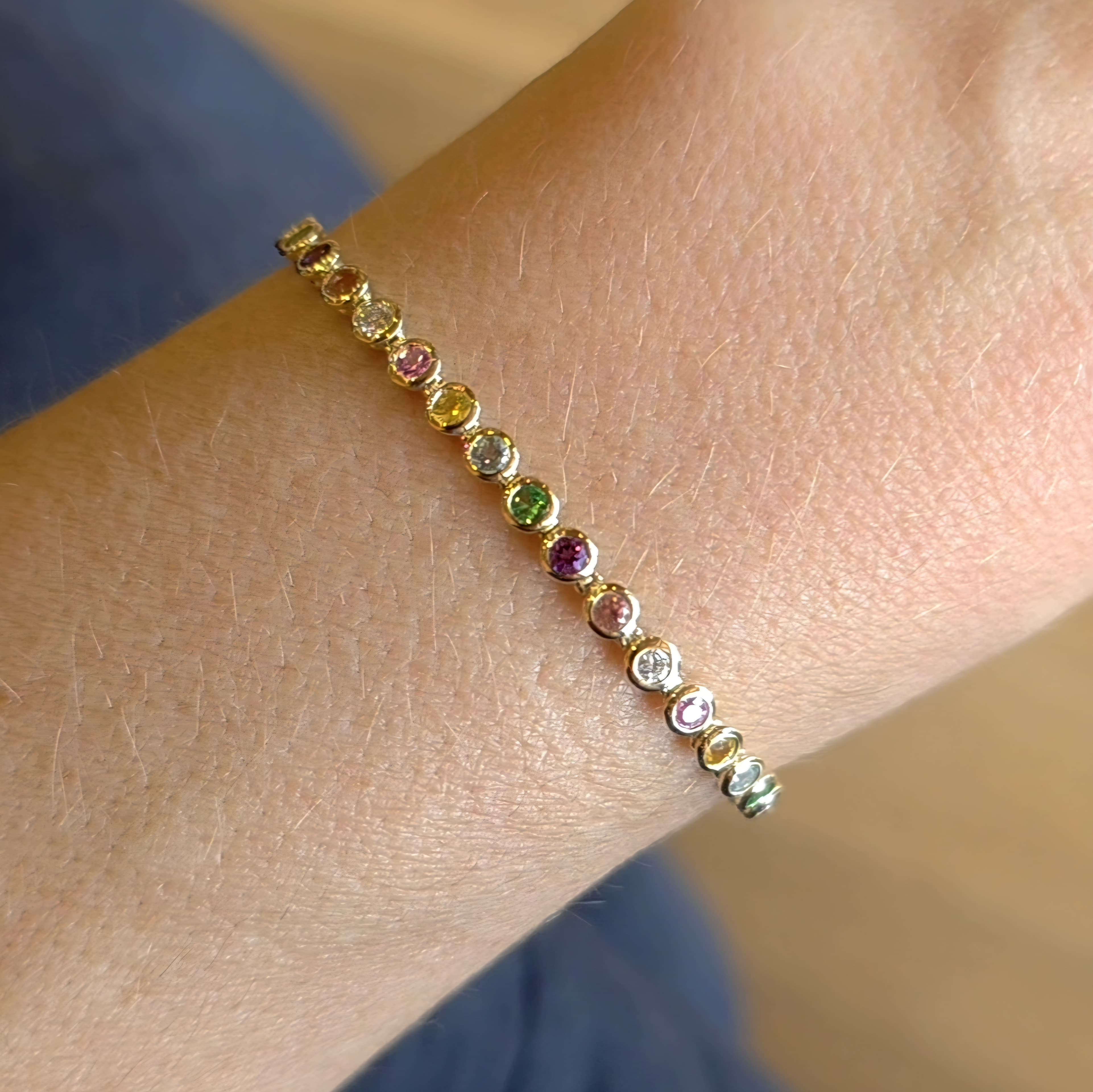 Faith Jewels Rainbow Tennis Bracelet featuring a vibrant mix of aquamarine, sapphires, white diamonds, garnet, peach, and amethyst gemstones totaling 2.80 carats, set in a sleek yellow gold chain