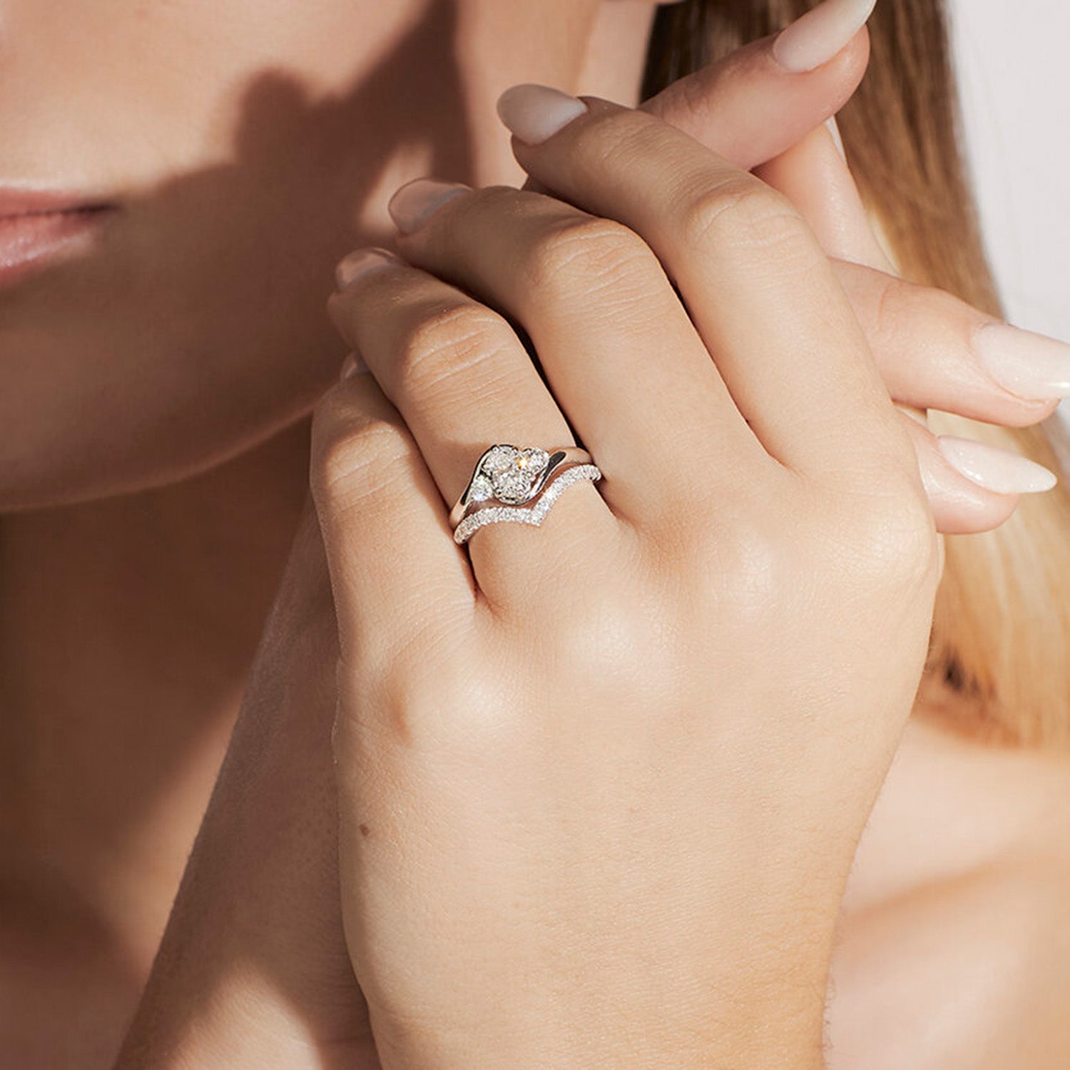 Faith Jewels Rue diamond engagement ring with a round brilliant-cut center diamond, flanked by two smaller brilliant-cut diamonds, featuring a twist band design, stacked with Faith Jewels V-Curve wedding band