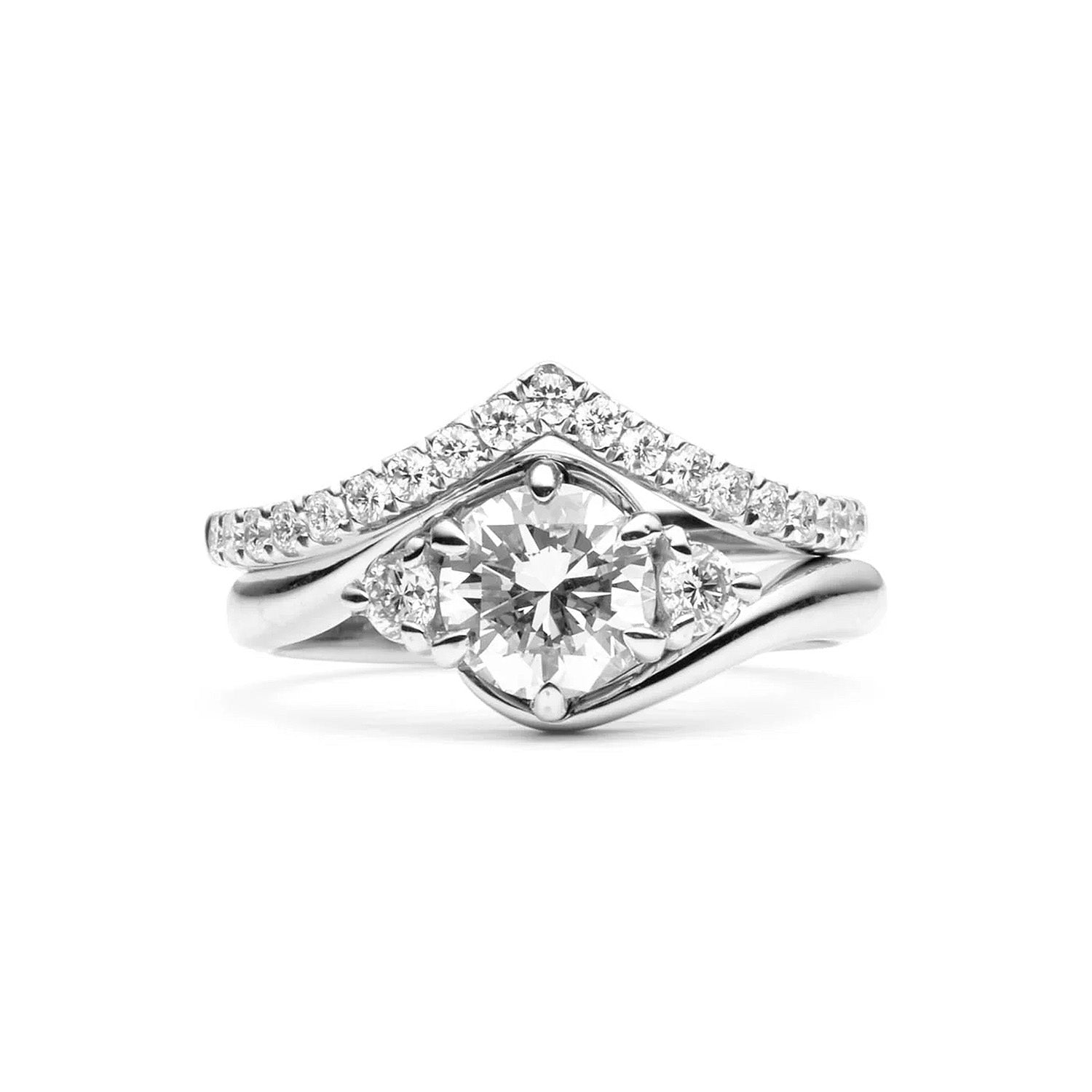 Faith Jewels Rue diamond engagement ring with a round brilliant-cut center diamond, flanked by two smaller brilliant-cut diamonds, featuring a twist band design, stacked with Faith Jewels V-Curve wedding band.