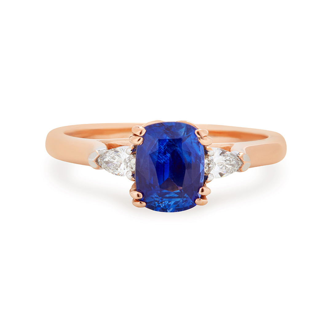 Sheree trilogy engagement ring featuring a royal blue oval-cut sapphire flanked by pear-cut white diamonds in rose gold band