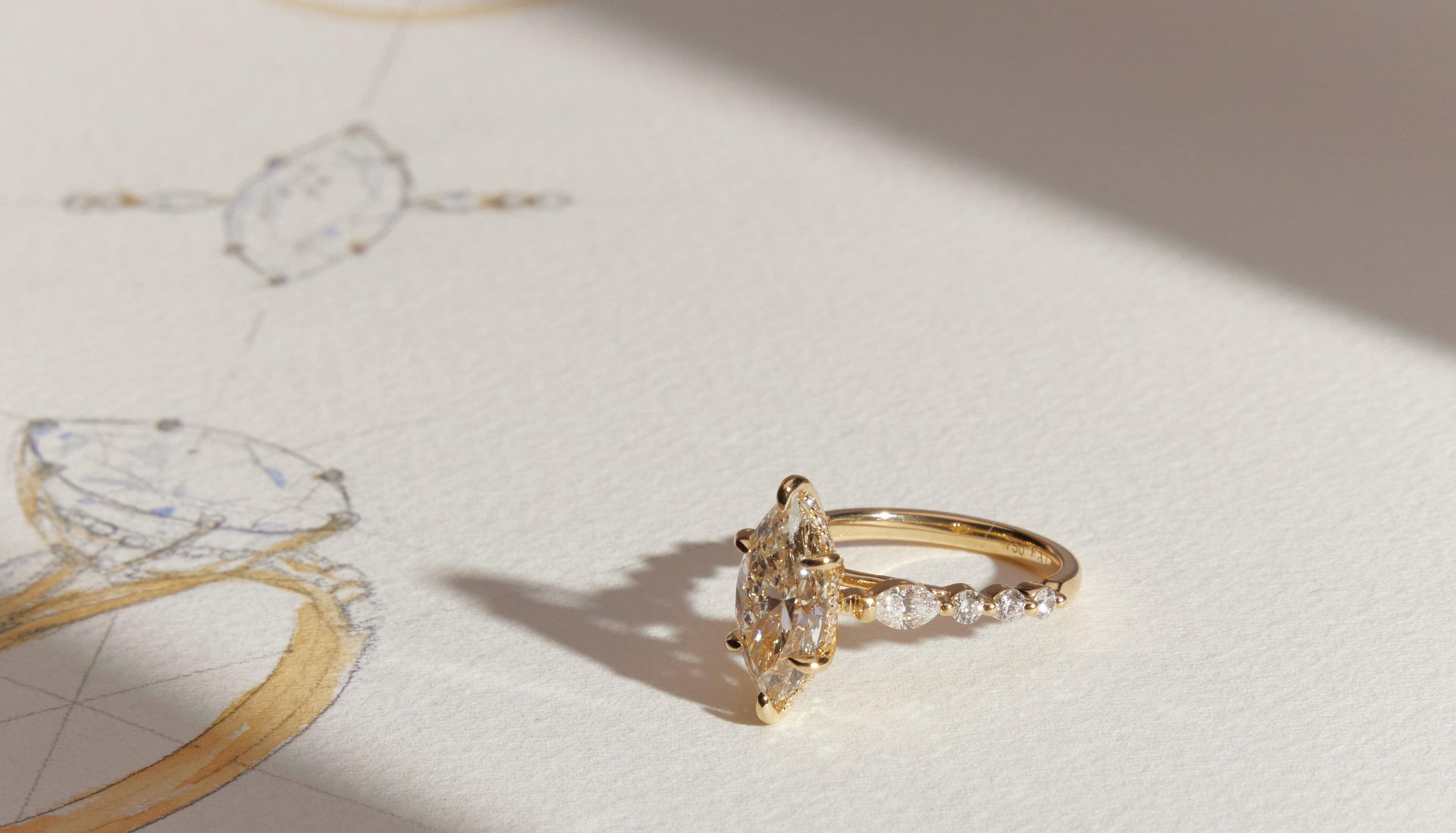 Marquise-cut diamond ring in yellow gold displayed on hand-sketched jewellery drawing