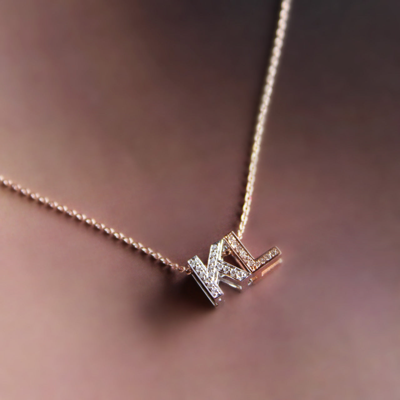 Bespoke pendant necklace with diamond-adorned initials "K" in white gold and "L" in rose gold on rose gold chain.