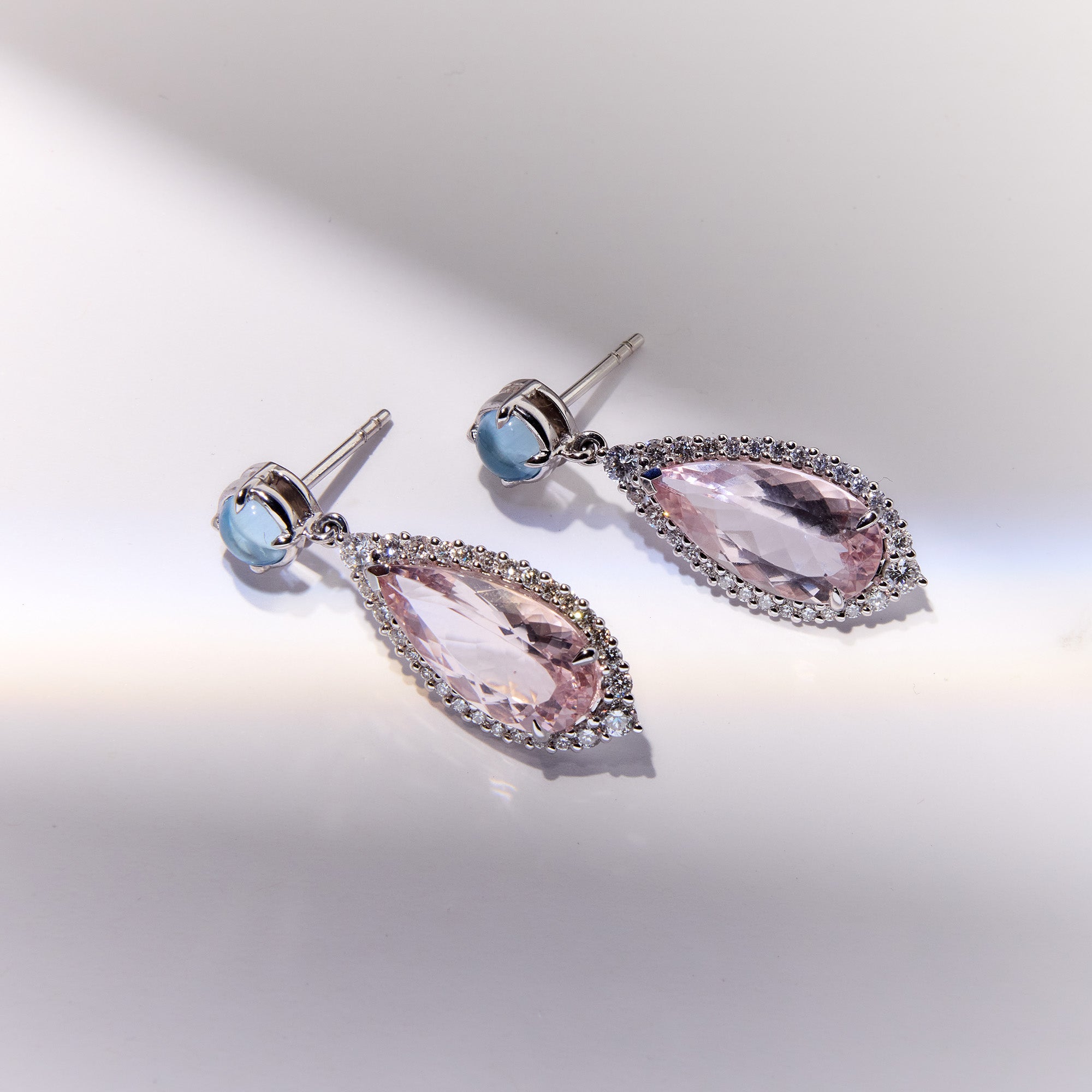White gold earrings featuring aquamarine cabochons, morganite drops, and diamond halo