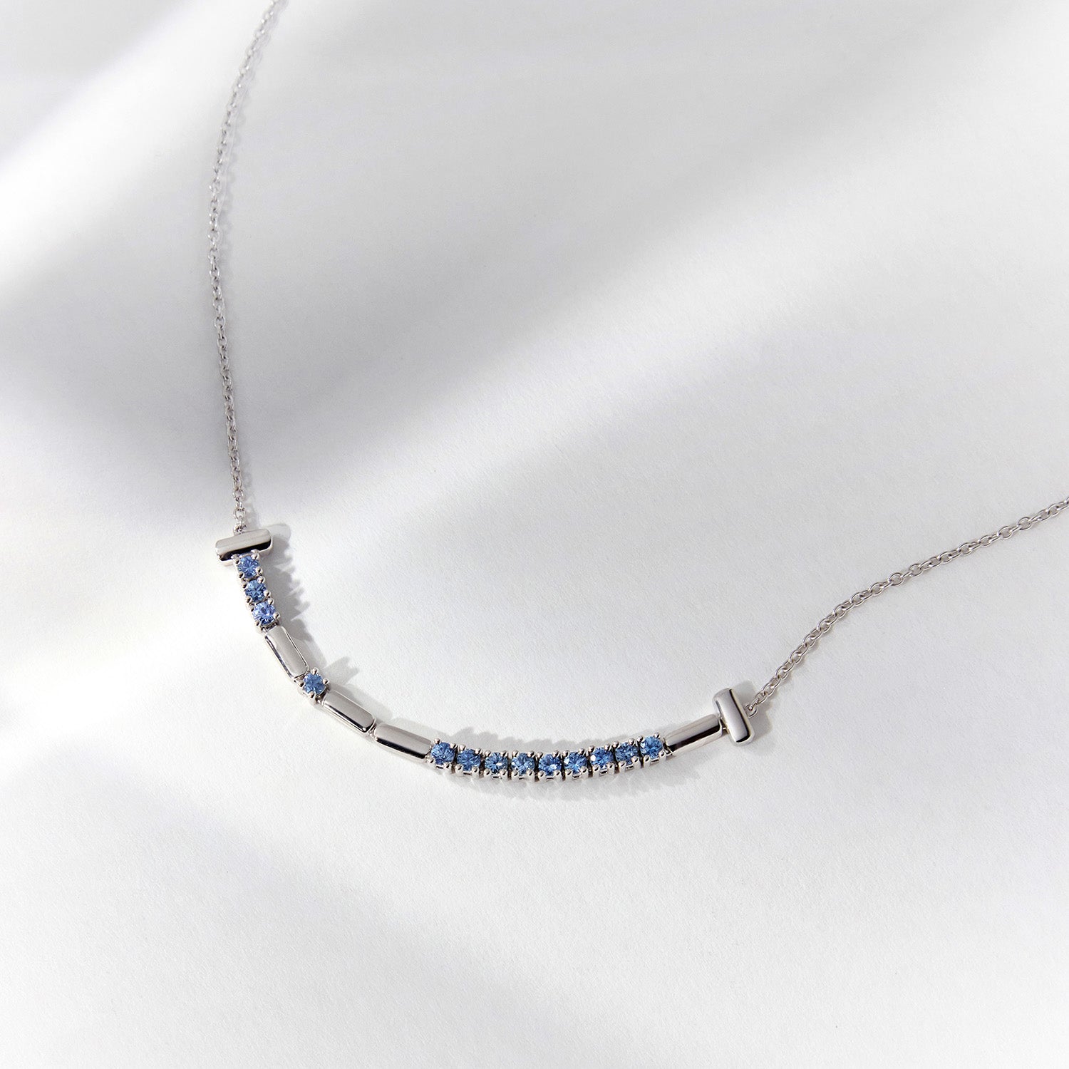 White gold necklace with aquamarine stones set in dots and dashes to depict a Morse Code arrangement.