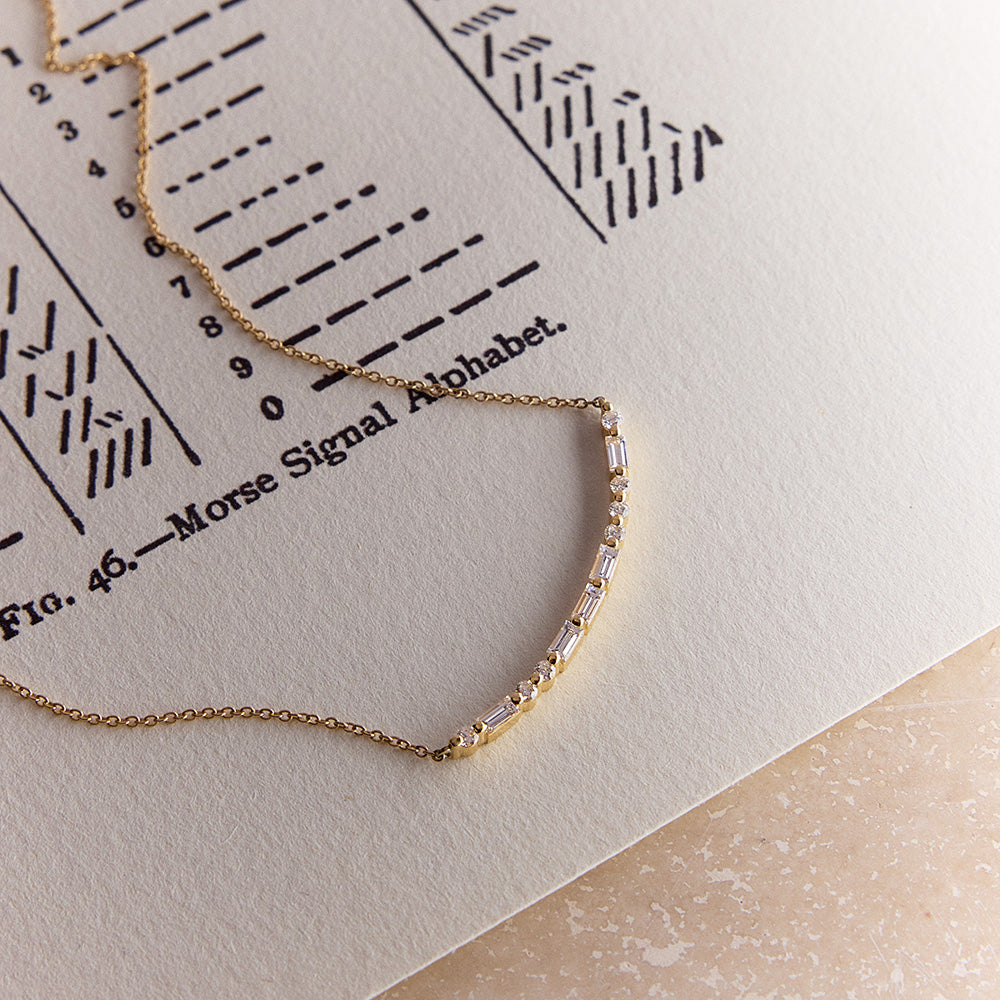 Faith Jewels 18k Yellow gold bar necklace with round and baguette diamonds spelling “LOVE” in Morse code.