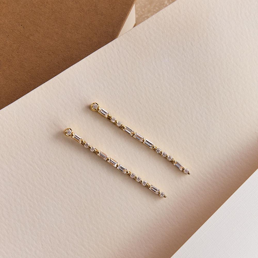 Faith Jewels Yellow gold drop earrings with round and baguette diamonds spelling “LOVE” in Morse code.