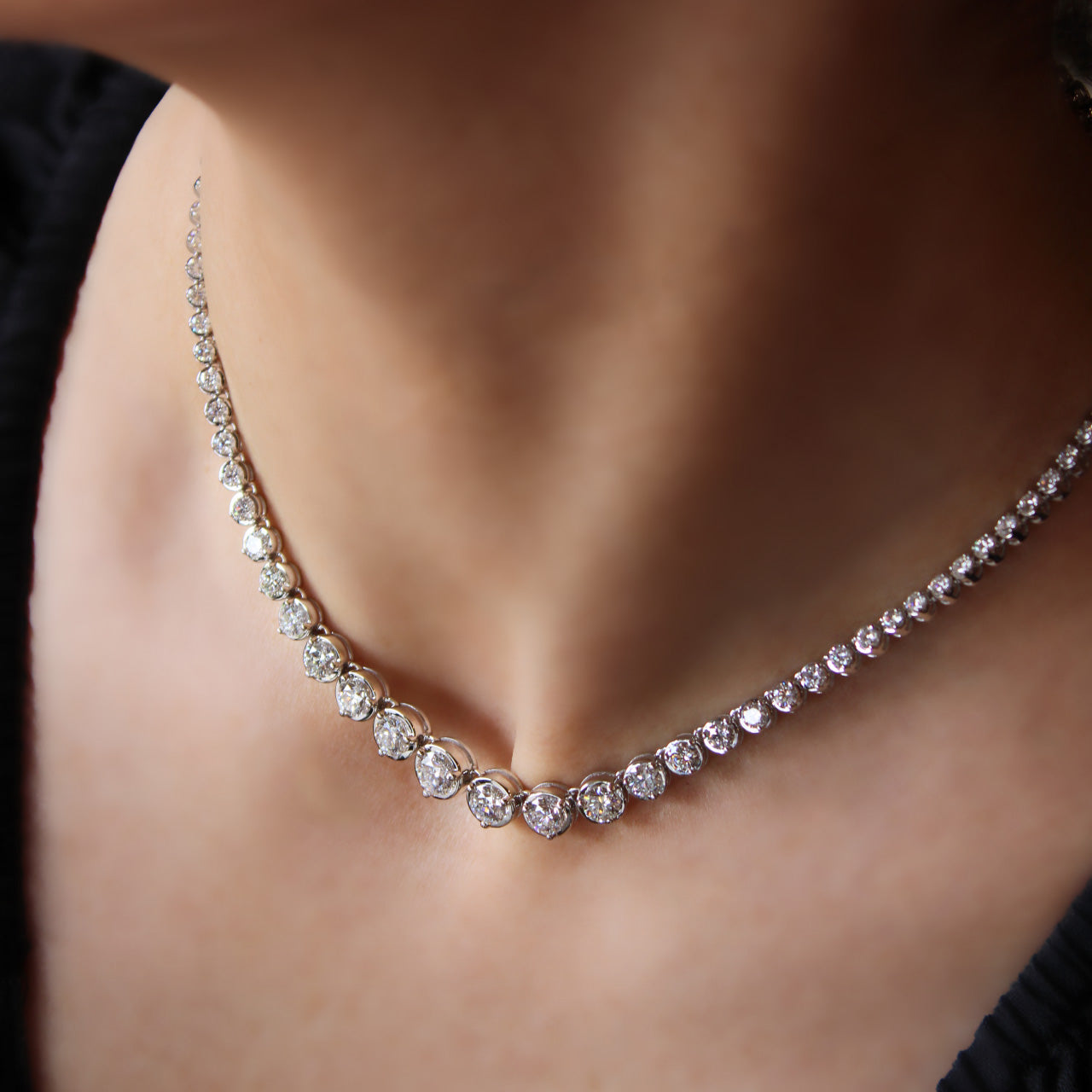 Bespoke graduated diamond tennis necklace with “Q” initial clasp in elegant design, worn on model.