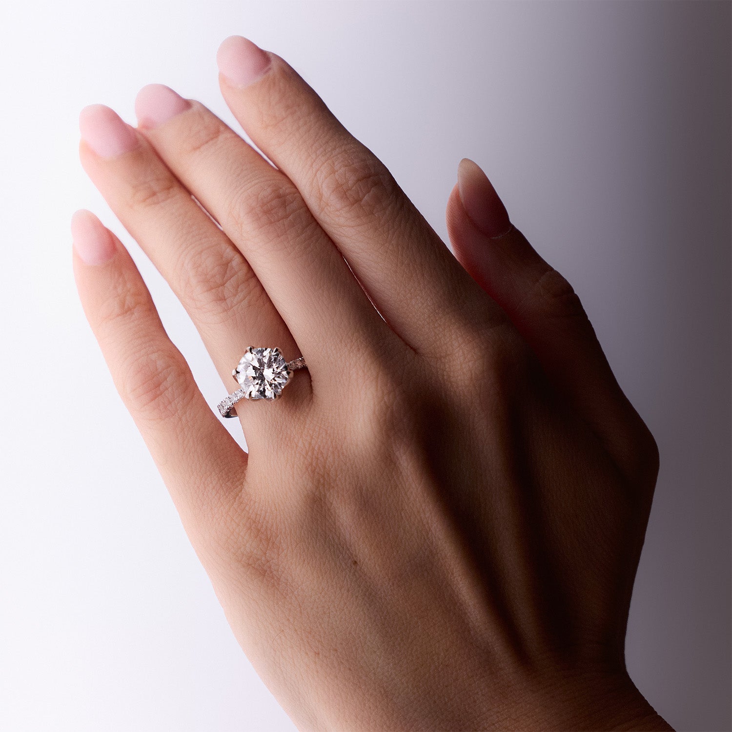 Sylvia diamond engagement ring with round brilliant-cut center stone and pavé band in white gold by Faith Jewels worn on hand model.