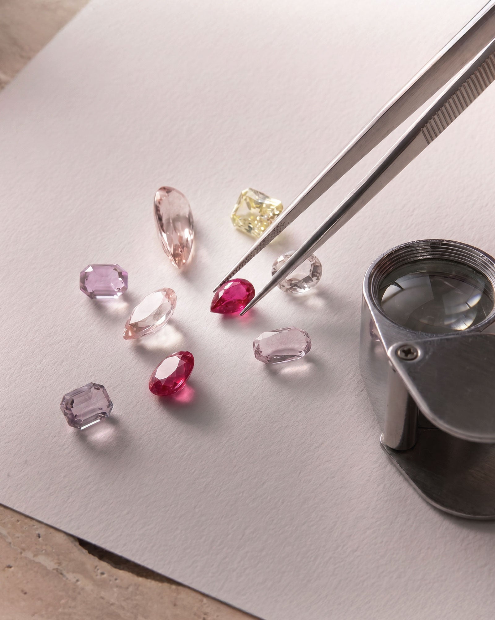 Loose gemstones being hand-selected with tweezers and a jeweller's loupe for Faith Jewels' bespoke jewellery design process