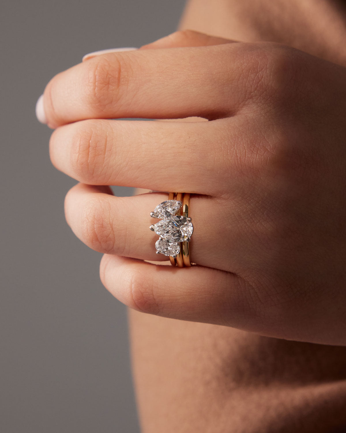 Faith Jewels Bridget engagement ring featuring a pear-shaped diamond held by a three-prong setting, elegantly set on a polished yellow gold band, stacked together with our Faith Jewels Duet wedding band