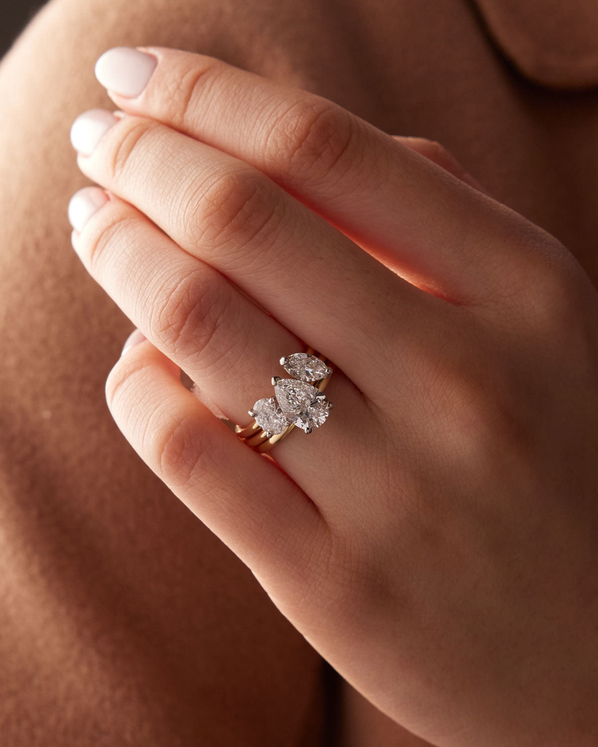 Faith Jewels Bridget engagement ring featuring a pear-shaped diamond held by a three-prong setting, elegantly set on a polished yellow gold band, stacked together with our Faith Jewels Duet wedding band