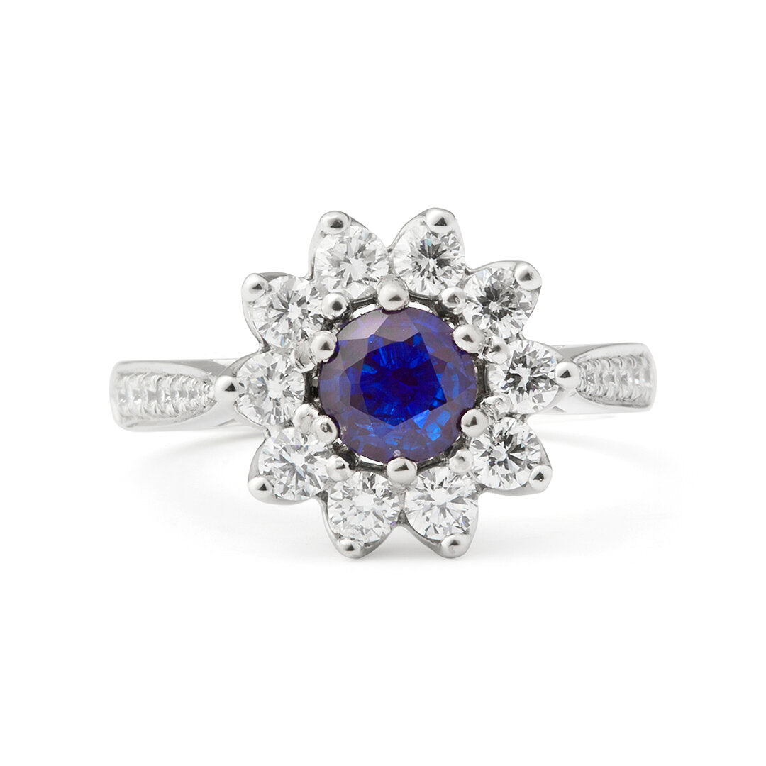 Faith Jewels Gina blue sapphire and diamond ring with a halo of brilliant cut diamonds surrounding a 0.50 carat blue sapphire, set in a half diamond grain-set band