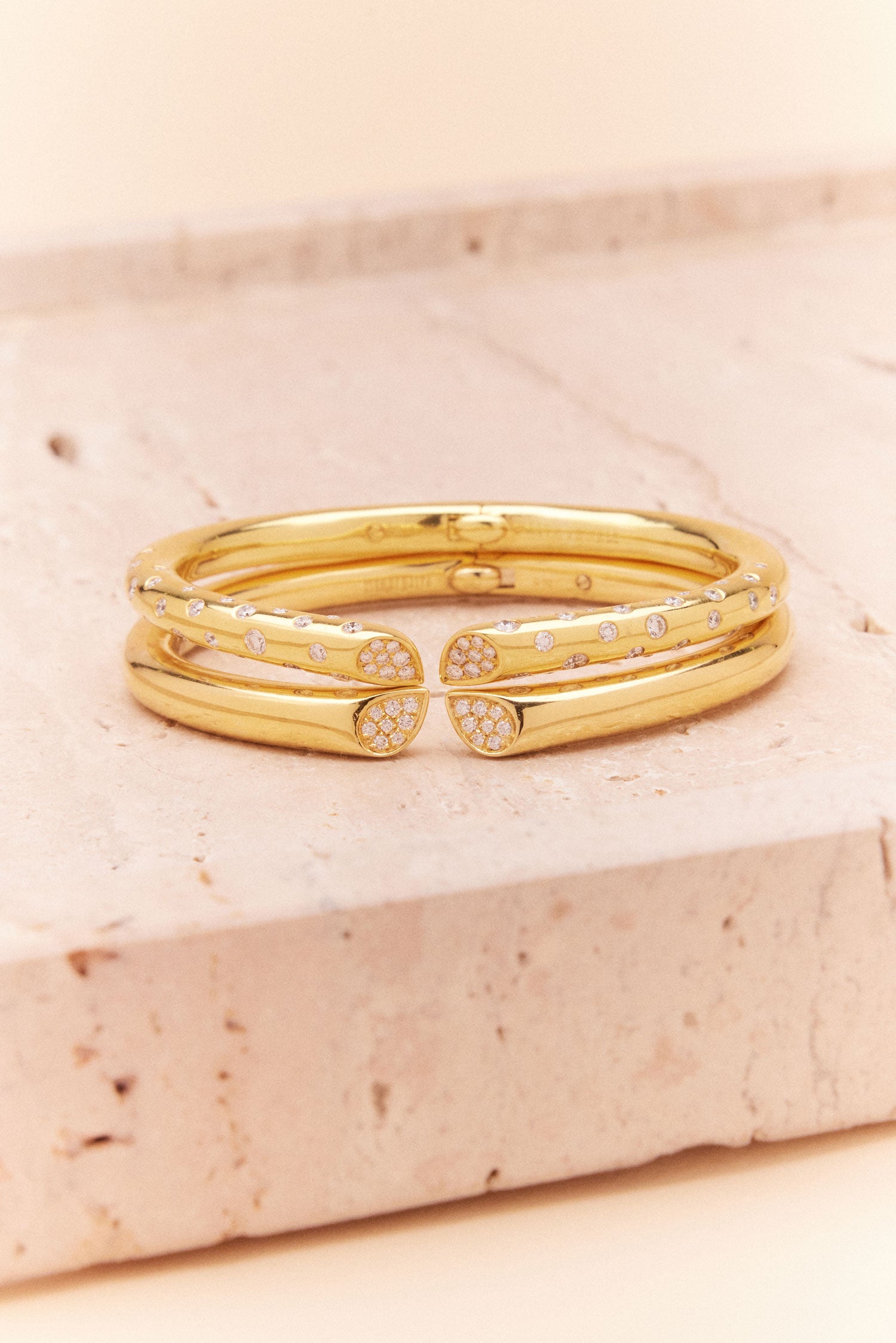 Yellow gold diamond bangle with pavé and hammer-set diamonds, heart-shaped lily motif from Whispers of Love, stacked together.