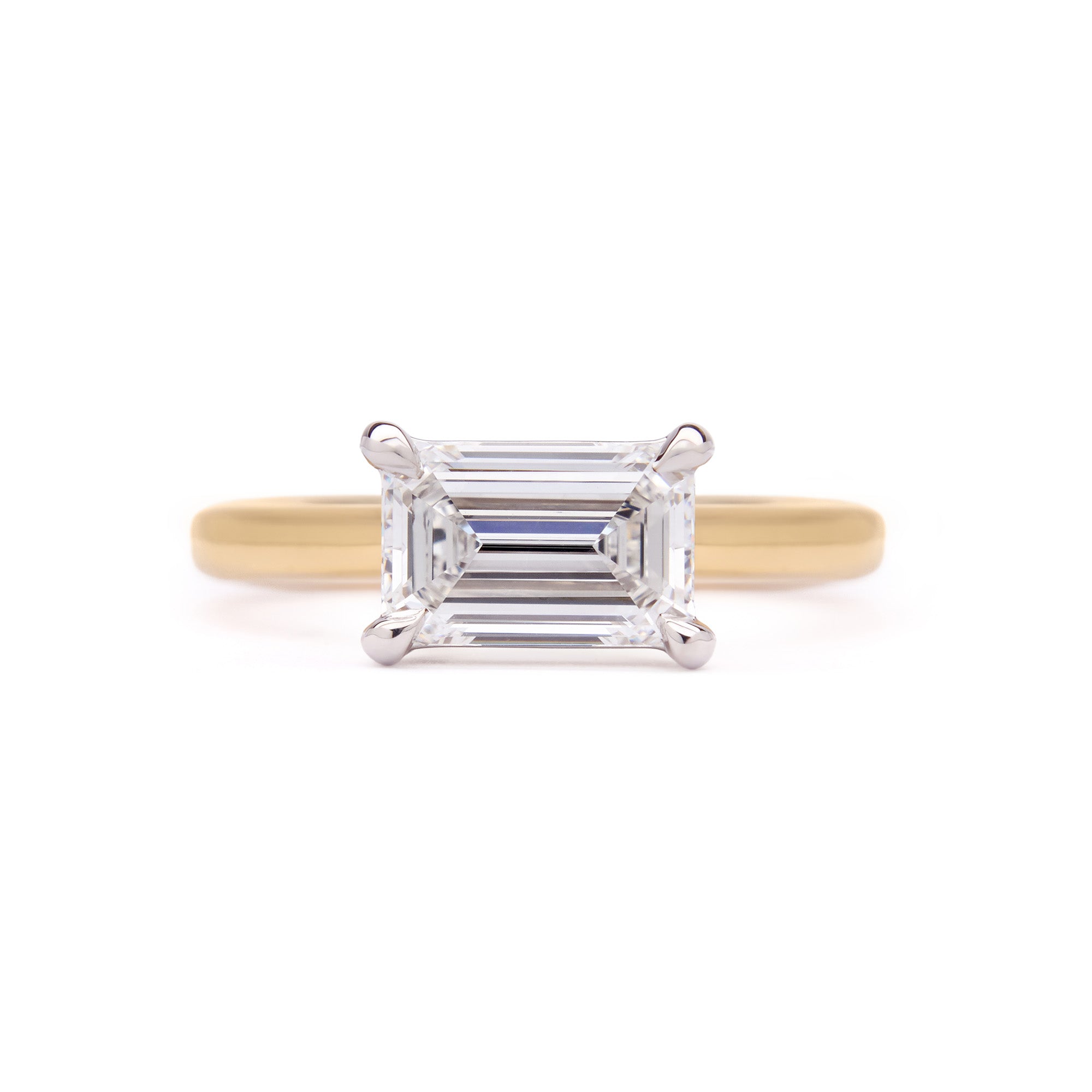 Emerald-cut East-West Engagement Diamond Ring in yellow gold with white gold claws, a modern yet timeless elegant design.