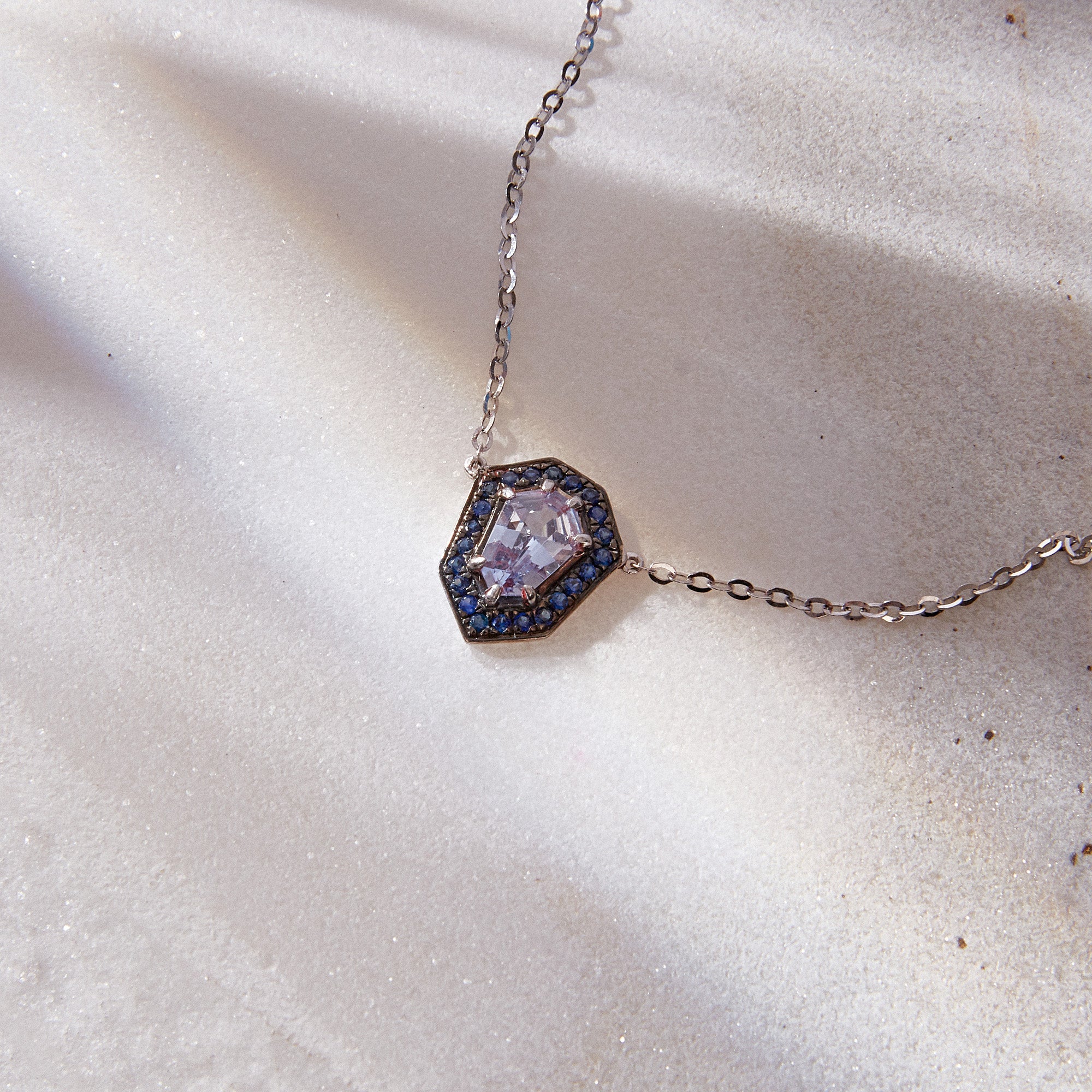 Dainty Kite Pendant Necklace in 18k white gold with 0.50ct light blue sapphire and halo of blue sapphires.