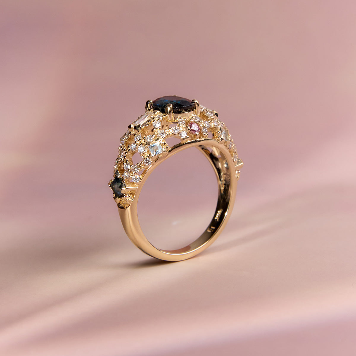 Gold dome ring with blue sapphire center, diamonds, and pink accents, side view