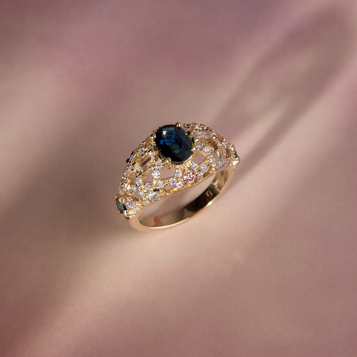 Gold dome ring with oval blue sapphire and diamond pave setting, side view