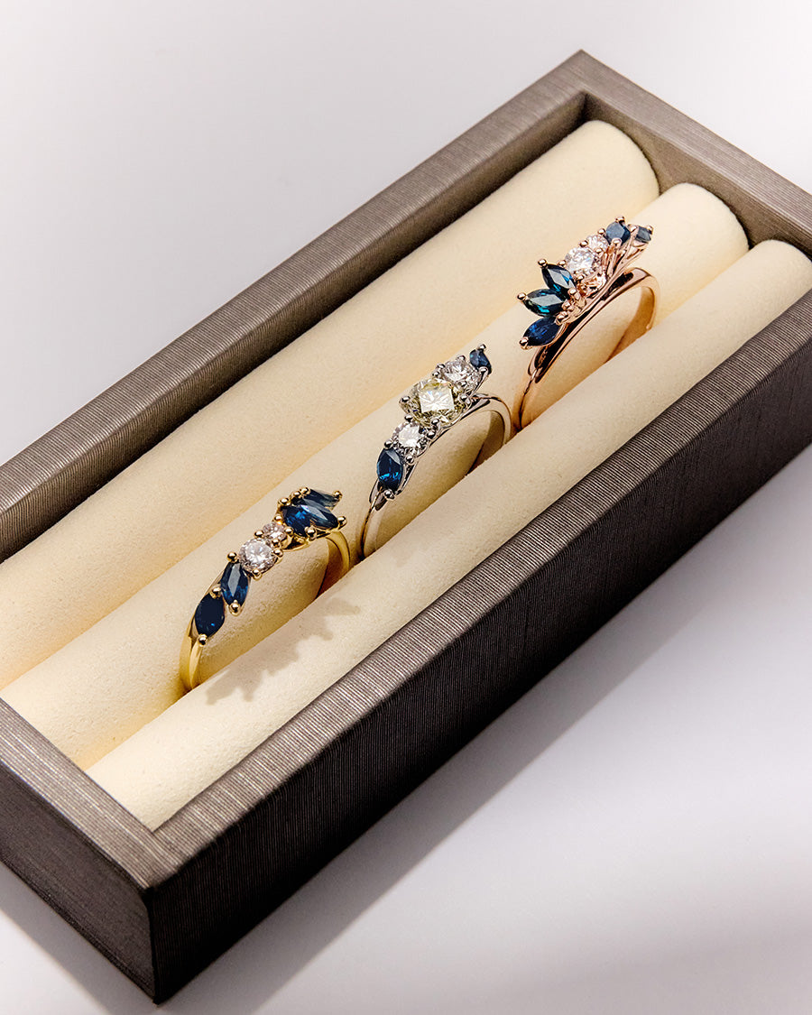 Custom and elegant three-generation heirloom ring set with diamonds and marquise blue sapphires in white, rose, and yellow gold in ring display box.