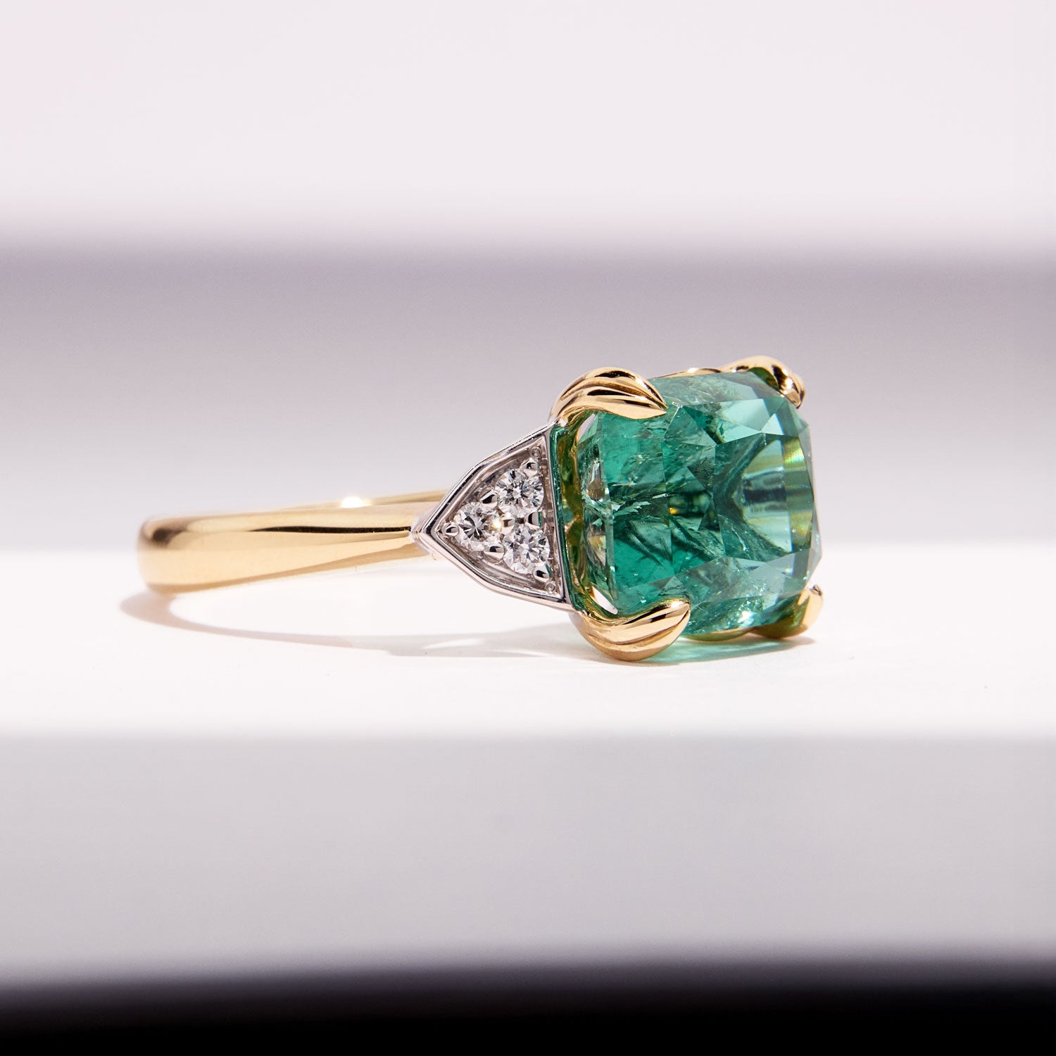Paraiba Tourmaline Ring featuring a cushion-cut blue-green gem with diamond sides, crafted in yellow and white gold for timeless elegance