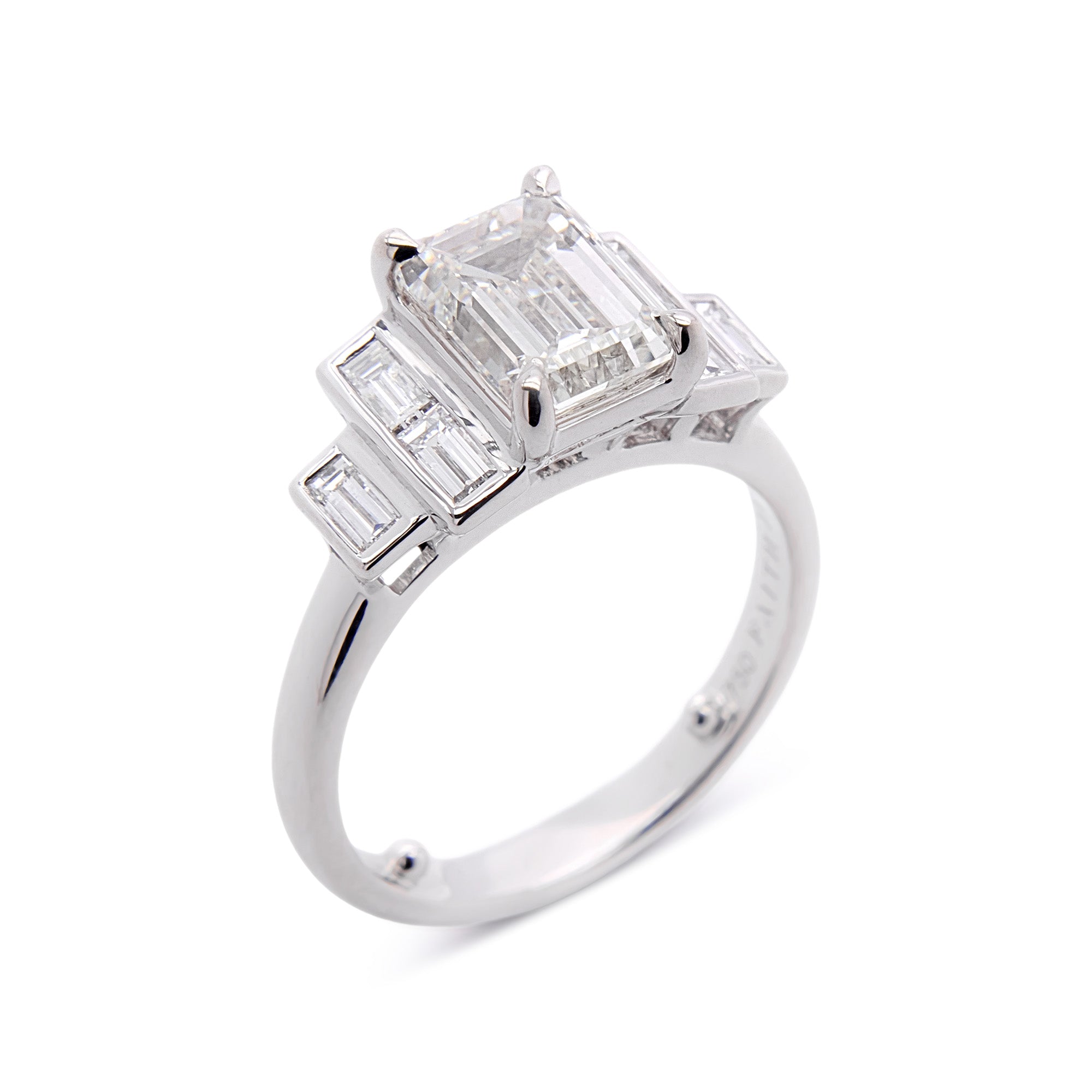 Diamond engagement ring with emerald-cut and baguette-cut diamonds on a white background