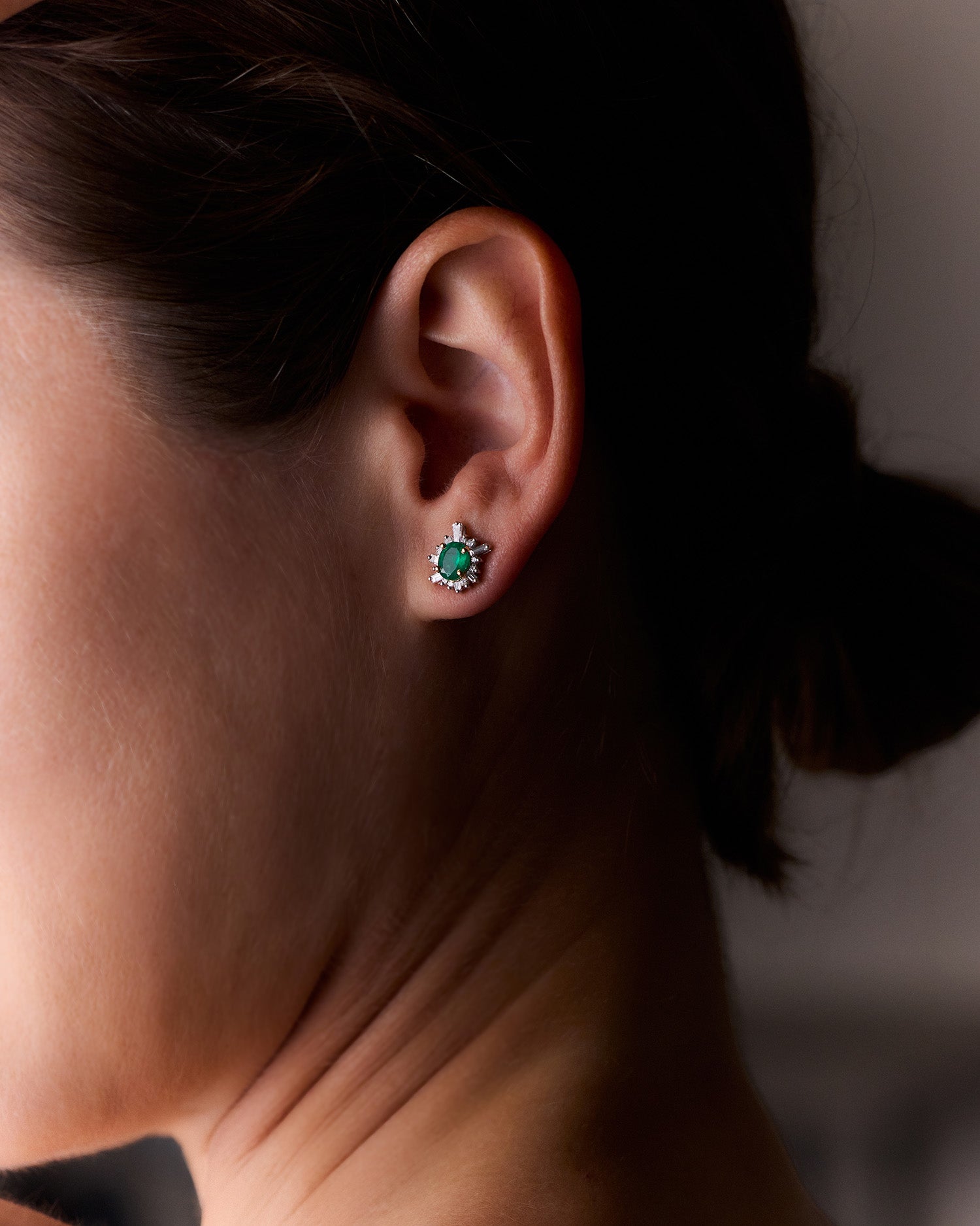 Oval-cut emerald sunburst earrings with white diamonds in yellow gold, radiant and elegant design, worn on model.