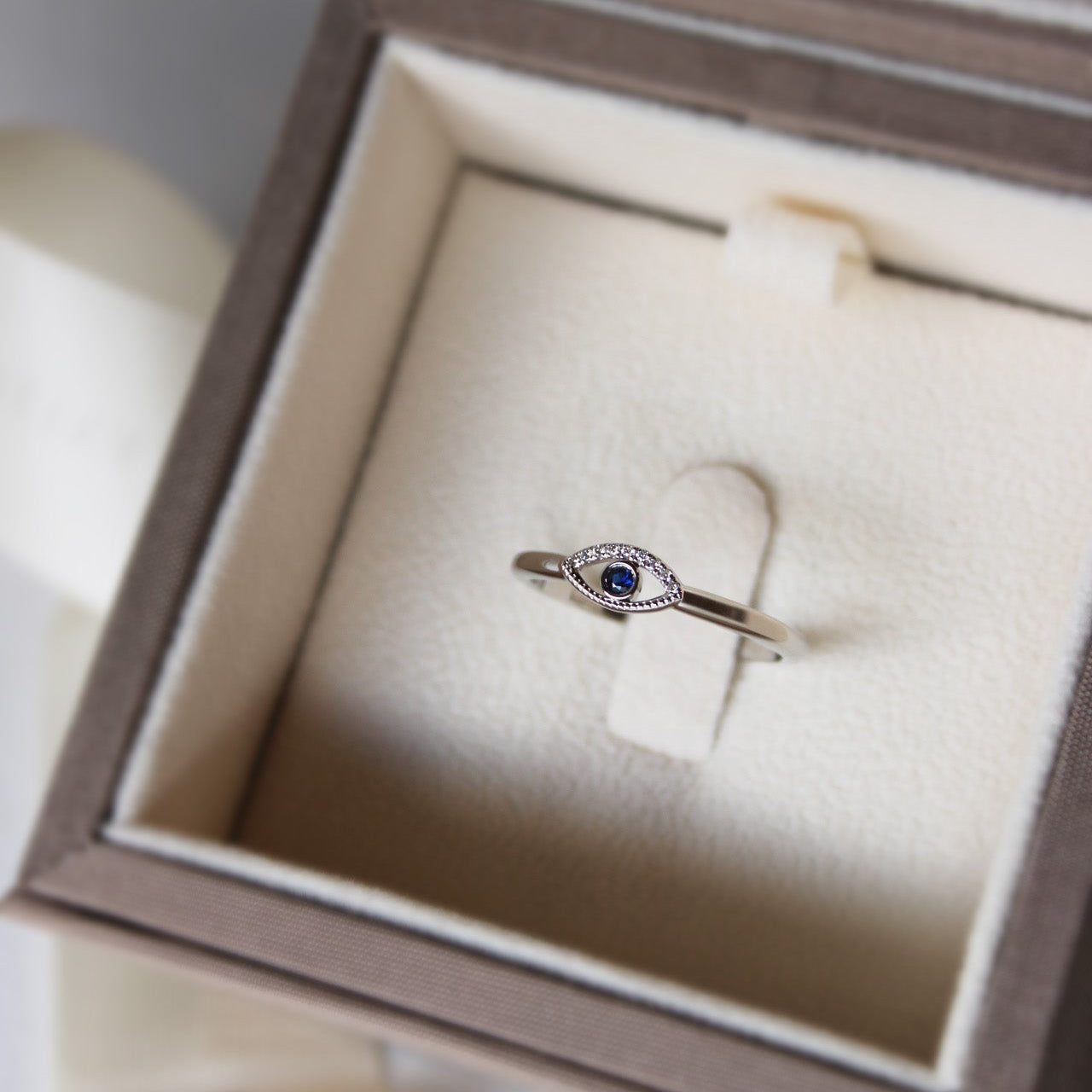 Minimal evil eye ring featuring a blue sapphire and white diamonds set in platinum.