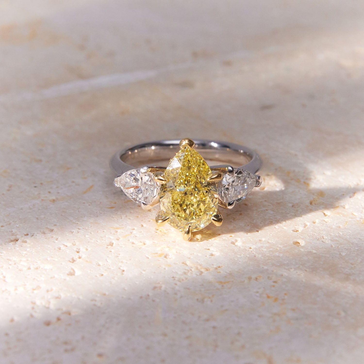 Belle Époque engagement ring with a pear-cut yellow diamond center, flanked by pear-cut white diamonds, set in 18k white gold