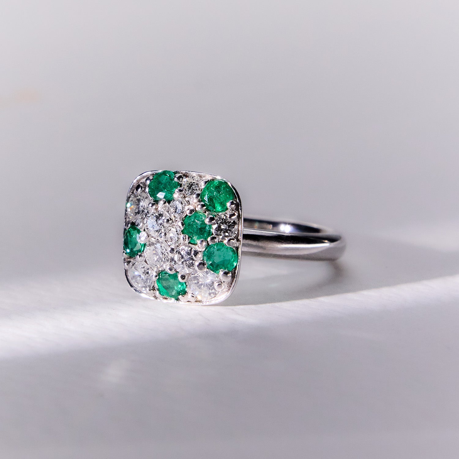 Faith Jewels 18k white gold ring featuring a mosaic-like pavé design with brilliant diamonds and vivid emeralds