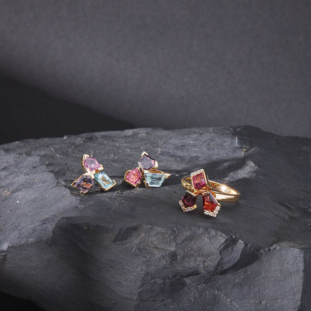 Set of colorful gemstone bouquet earrings and bouquet ring on a stone surface