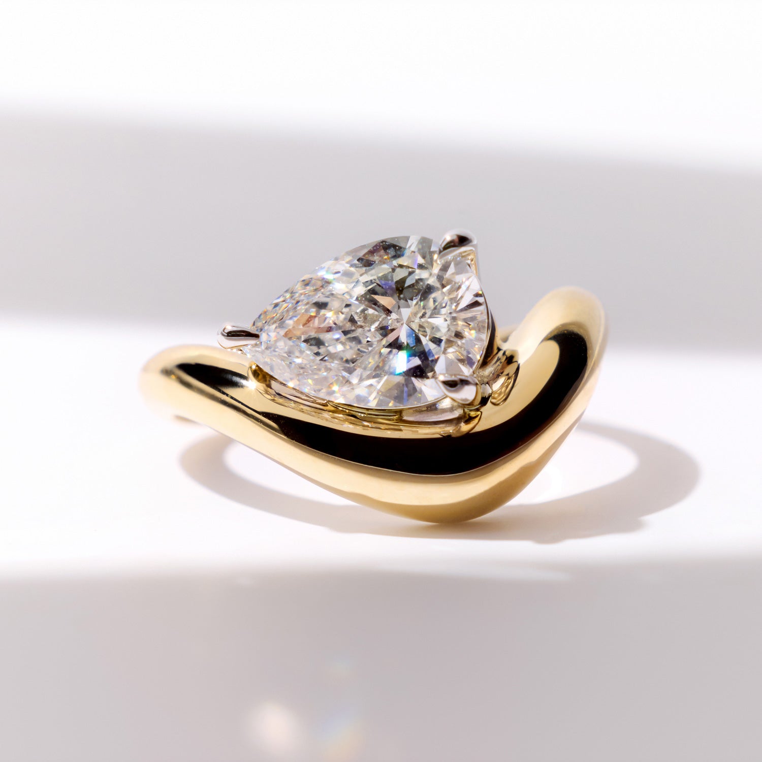 FJ Engagement Ring featuring a pear cut diamond set in a bold, curved yellow gold band with a sculptural, contemporary design