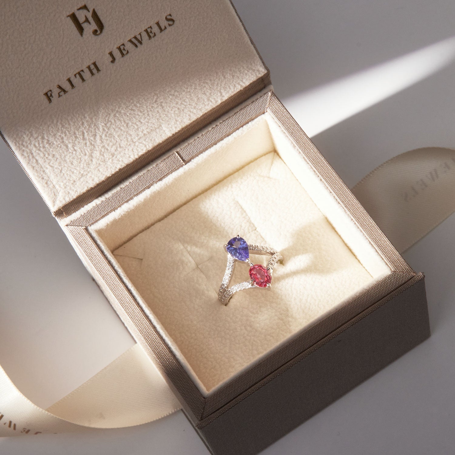 Faith Jewels Elsie ring in 18k white gold featuring a pear-cut tanzanite and a pink sapphire, set on a split diamond white gold band