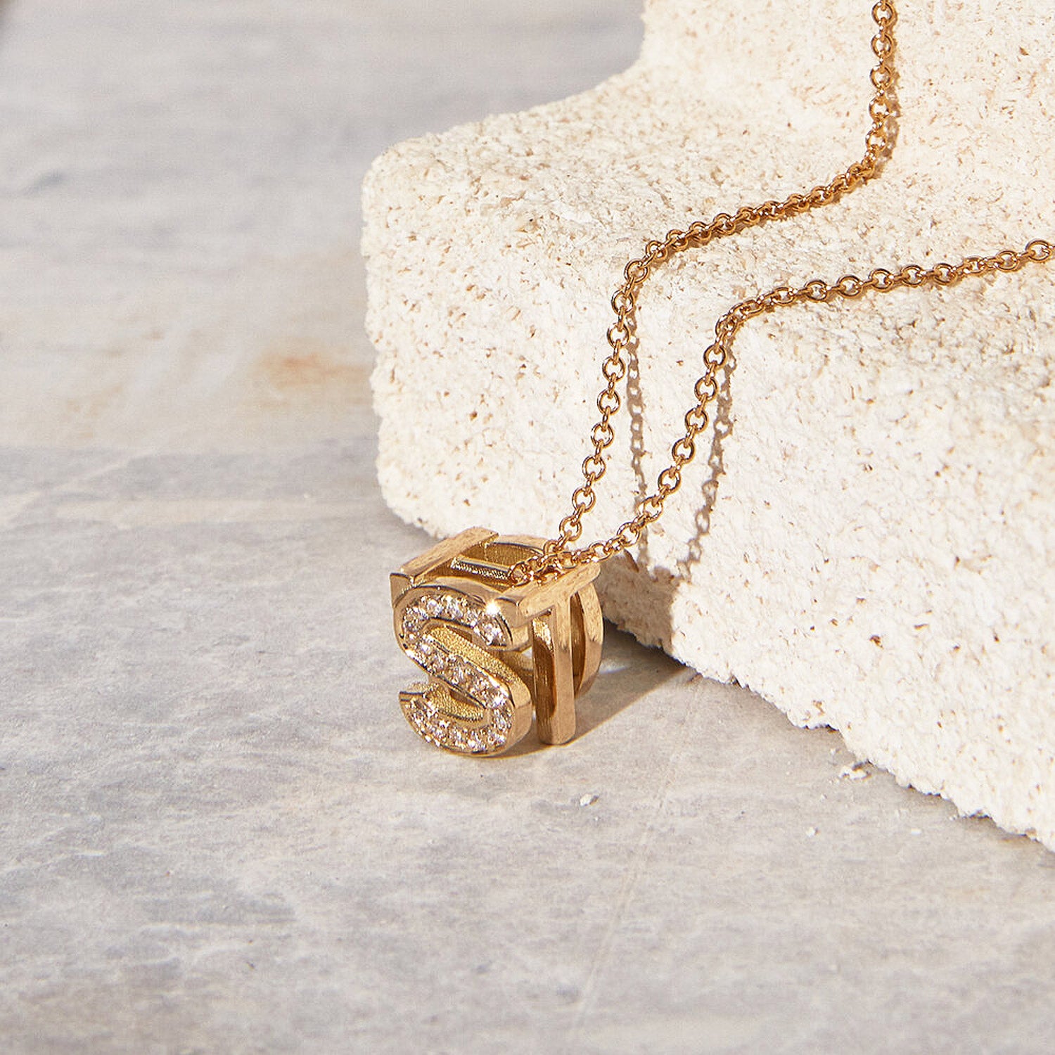Bespoke Initial Cube Pendant Necklace featuring a customizable 3D cube design with diamonds initial S and initial T, suspended from a yellow rose gold trace chain 