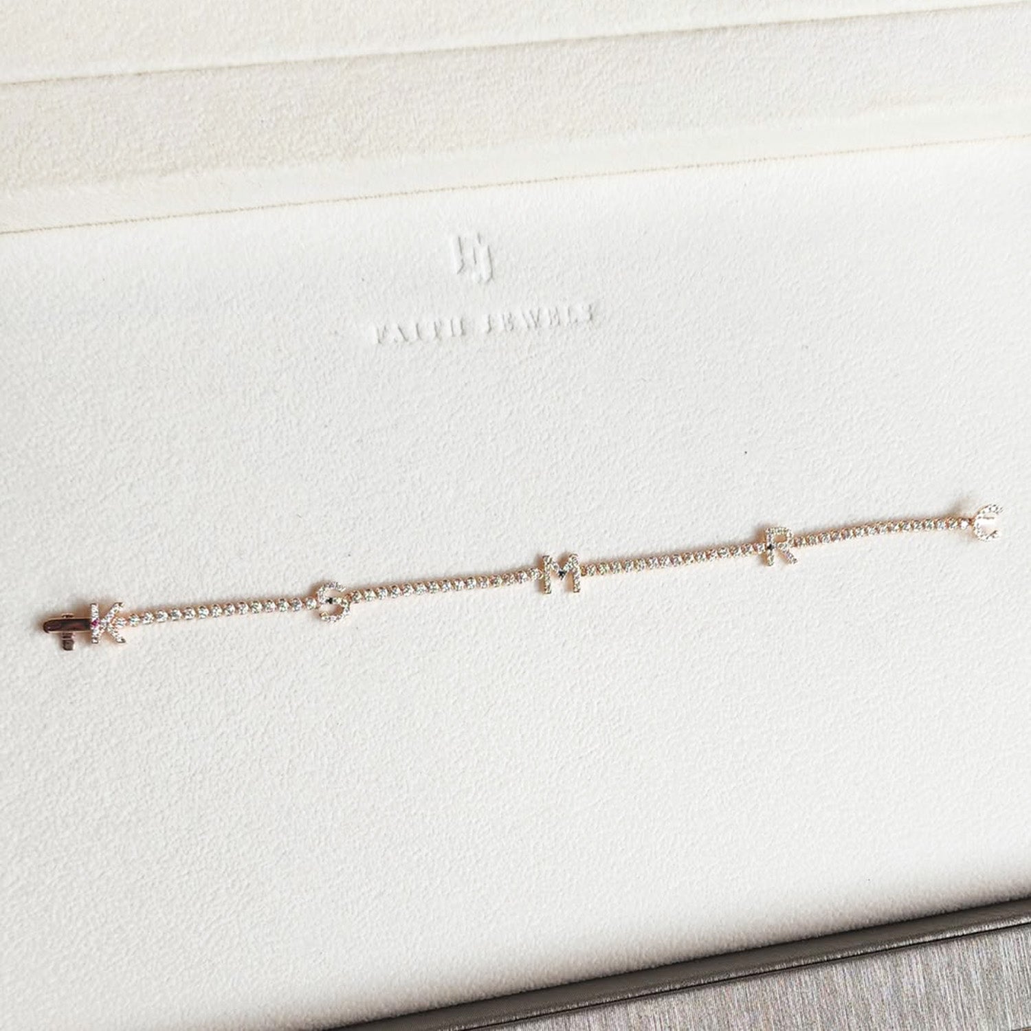 Faith Jewels bespoke initial diamond tennis bracelets in rose gold, each featuring a unique clasp shaped as a letter K, S, M, R and C — set with round brilliant-cut diamonds and red ruby and blue sapphires
