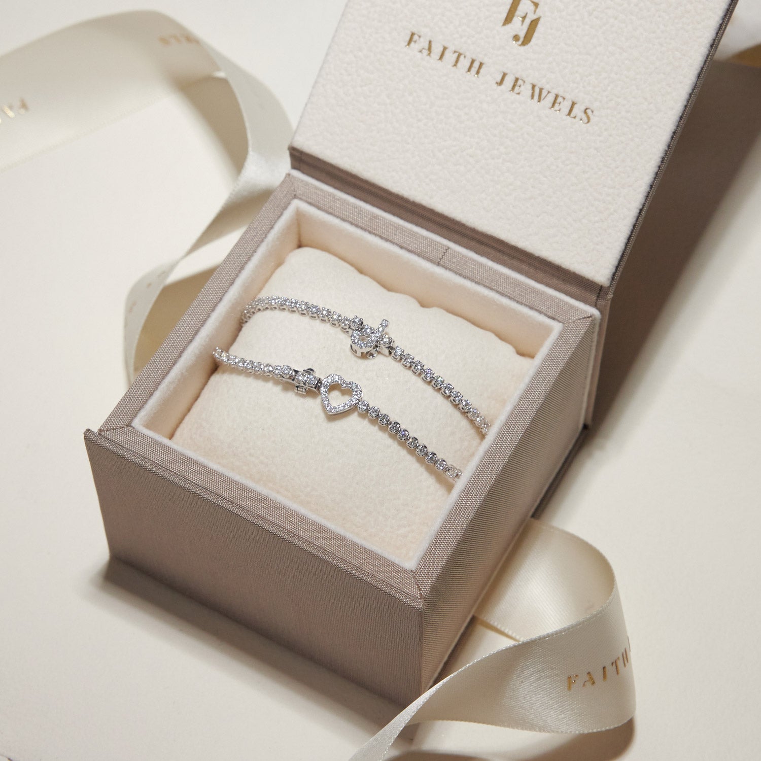 Faith Jewels bespoke initial diamond tennis bracelets in white gold, each featuring a unique clasp shaped as a letter J and heart symbol— set with round brilliant-cut diamond