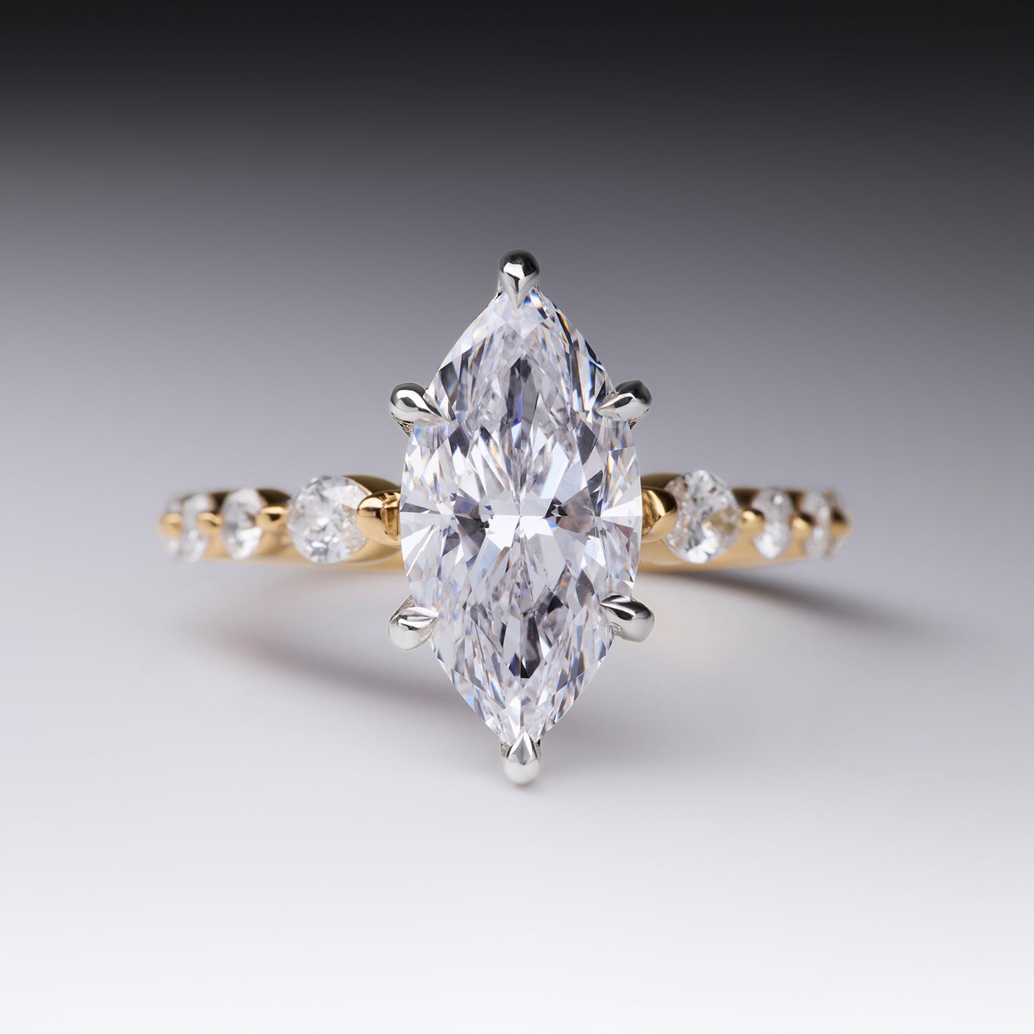 Julia Engagement Ring marquise-cut diamond engagement ring featuring a brilliant center stone with a gold band adorned with round accent diamonds by Faith Jewels